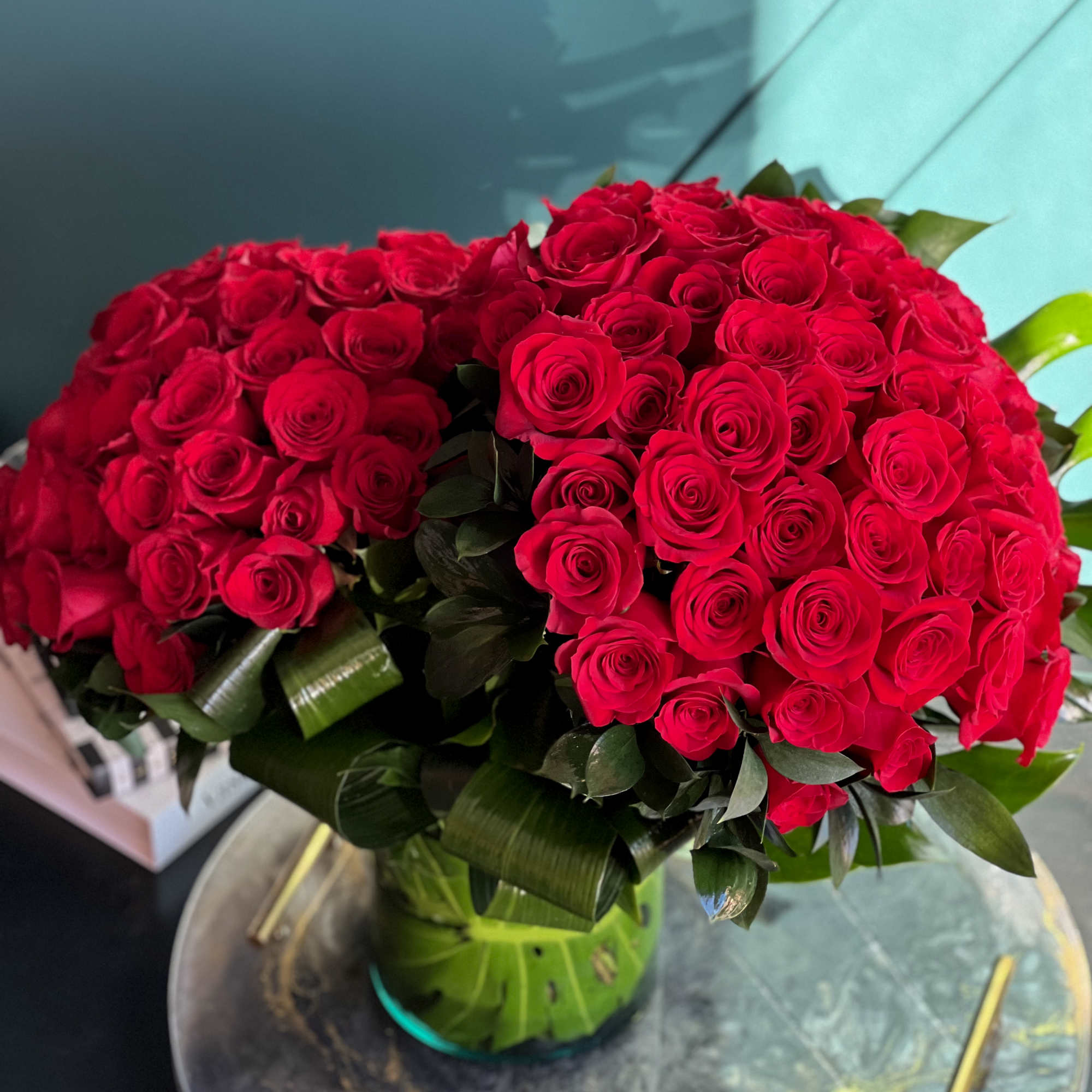 100 premium red roses in a clear vase with greenery accent 