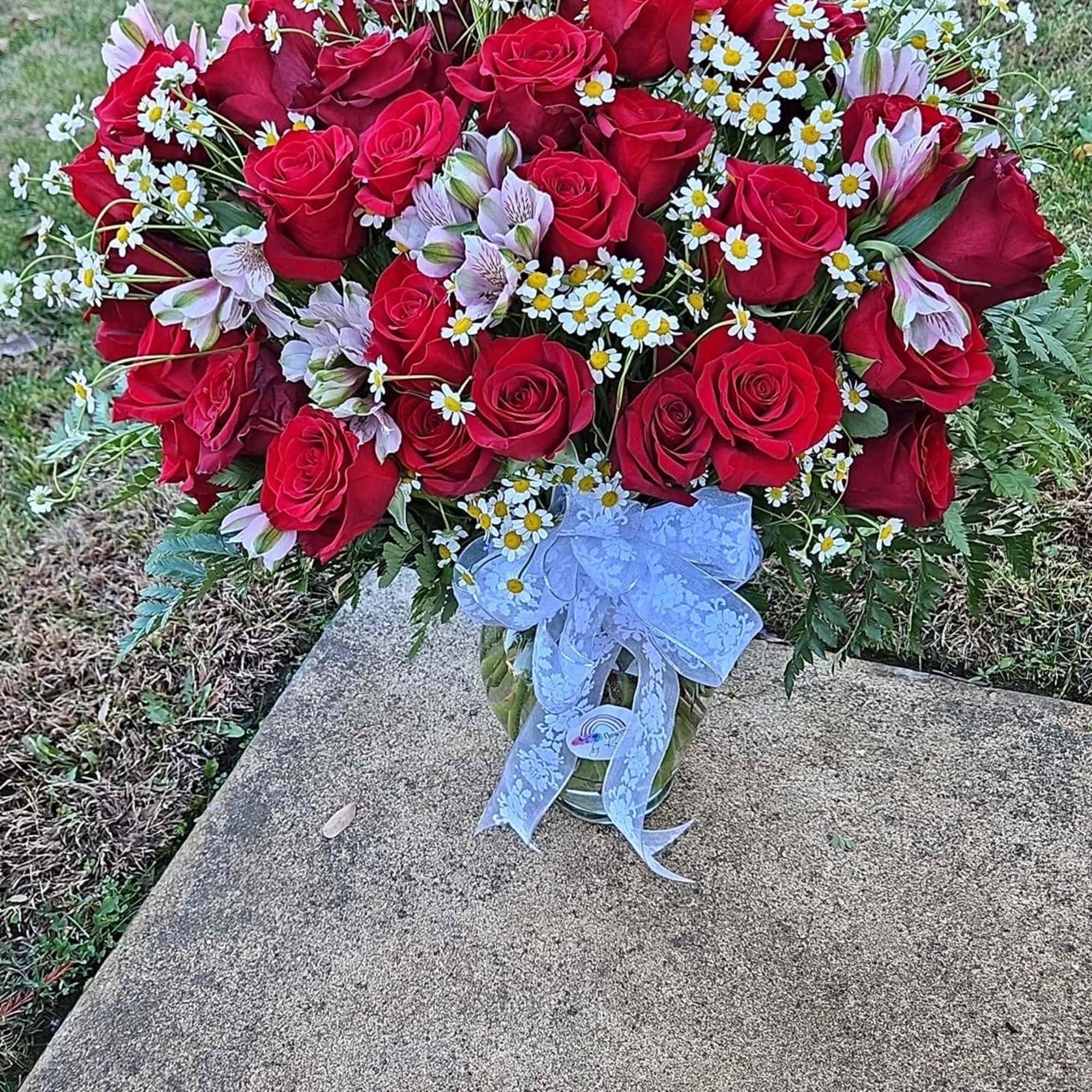 long-stem red roses in a vase mixed with filler flowers, filler, and