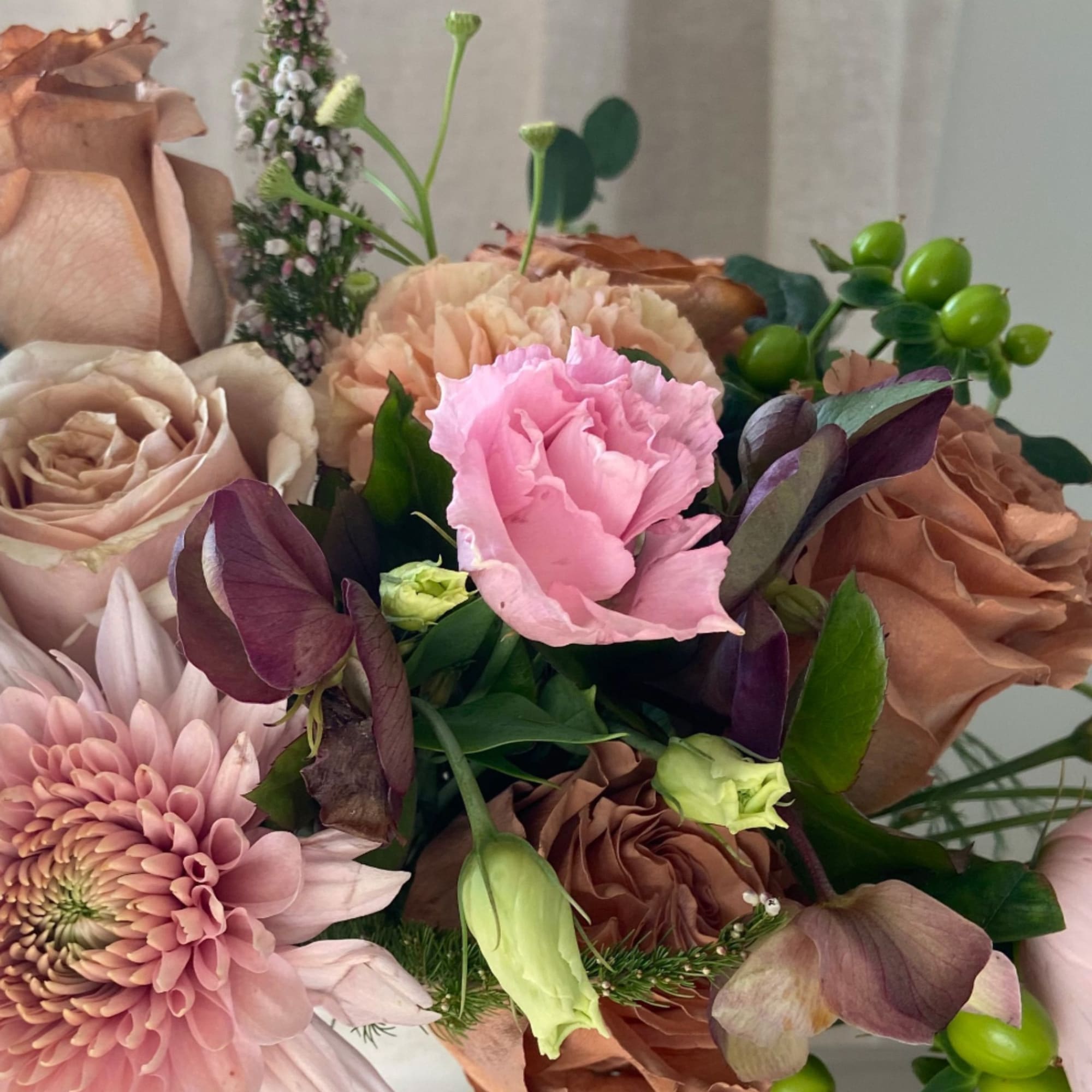 A soft, sun-washed arrangement featuring blush and camel garden roses, rich-toned hellebore