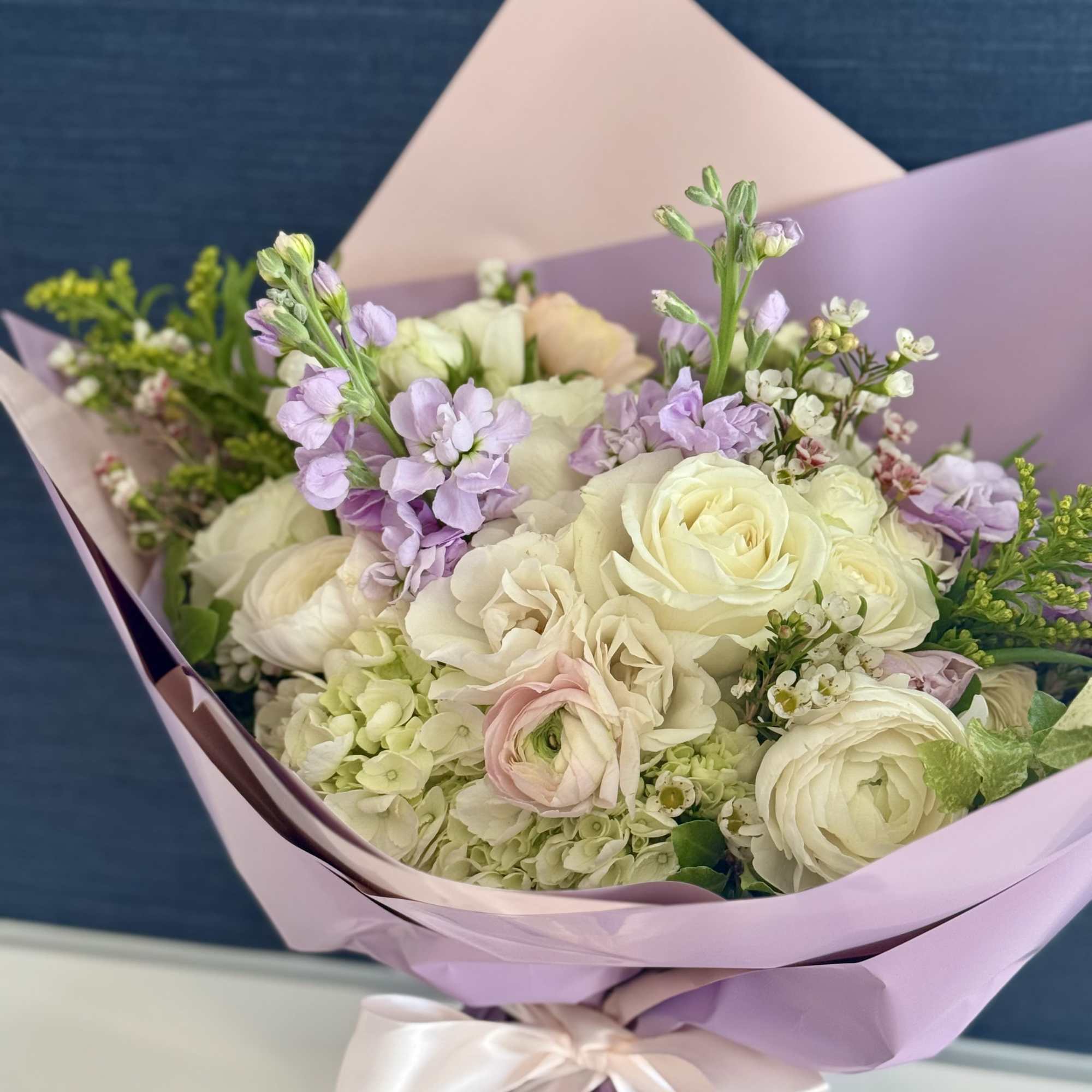 A hand tied arrangement in premium neutrals, soft lavender and blush. Florist