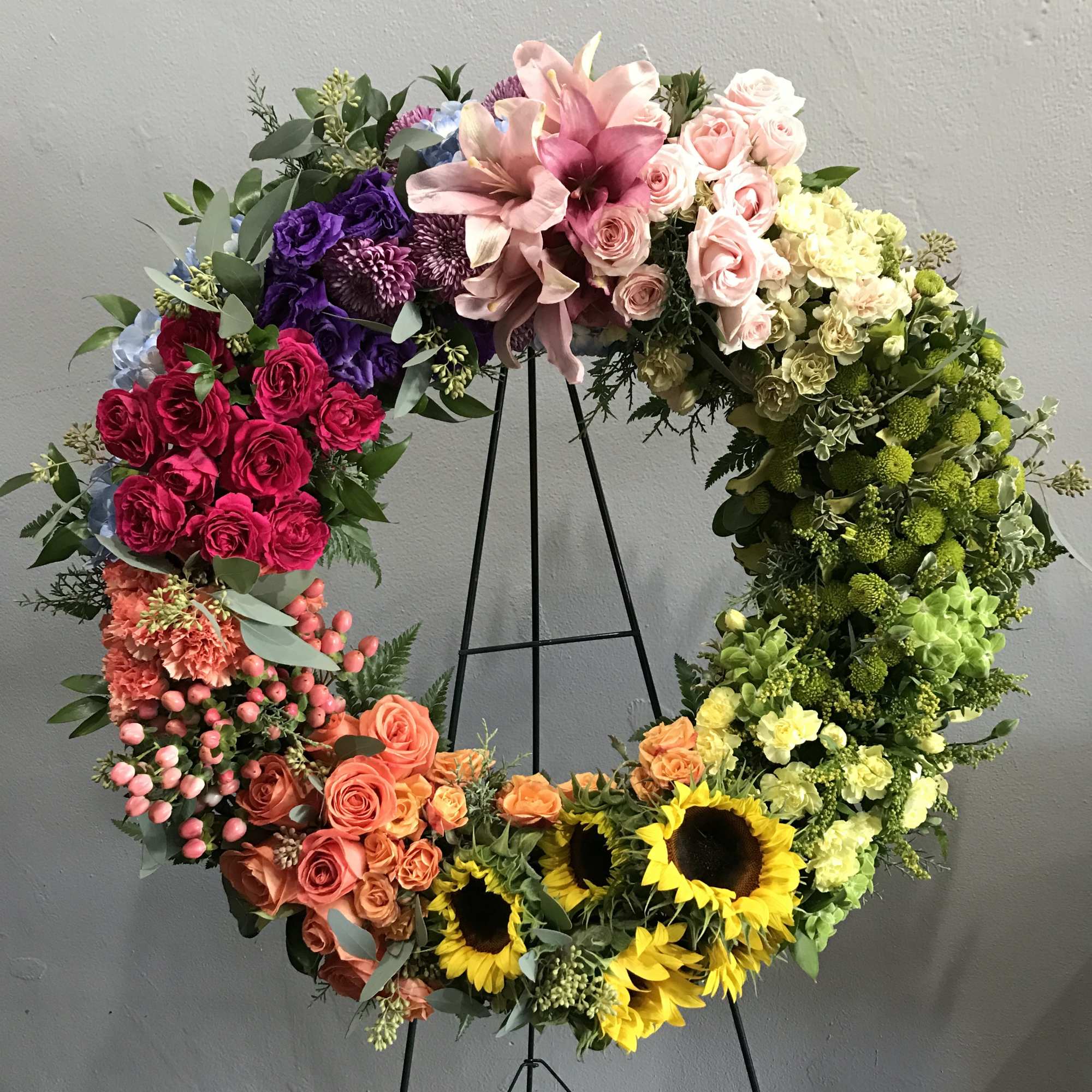 A circular wreath with warm, fun, colorful flowers. A demonstration of love