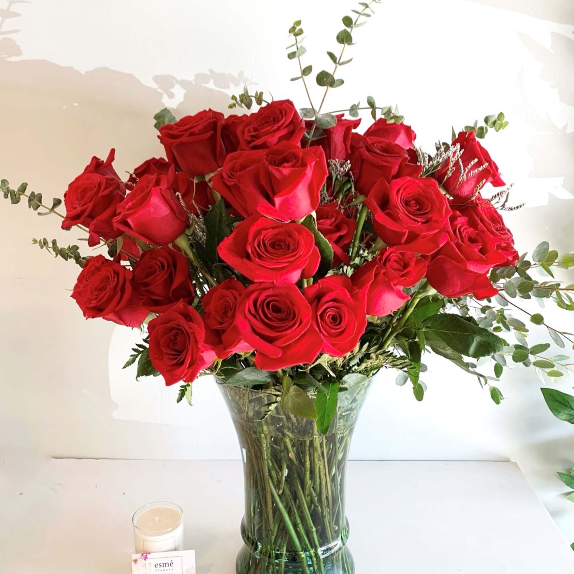 A lush arrangement of classic red roses in a tall clear vase