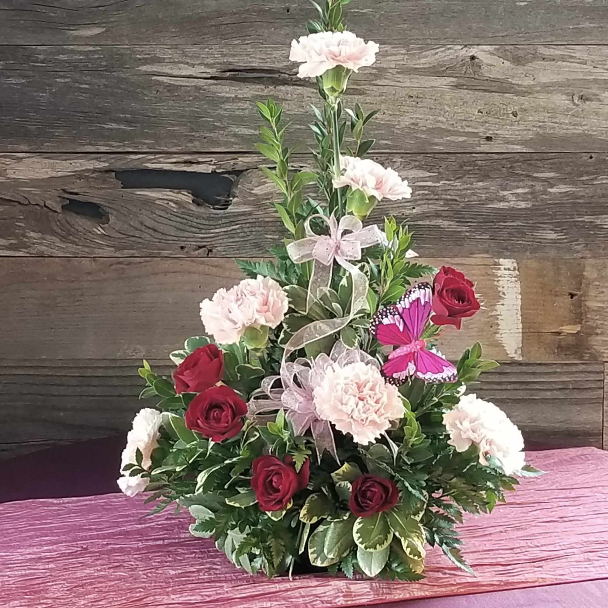 Carnations and spray roses on a bed of greenery, with bows and