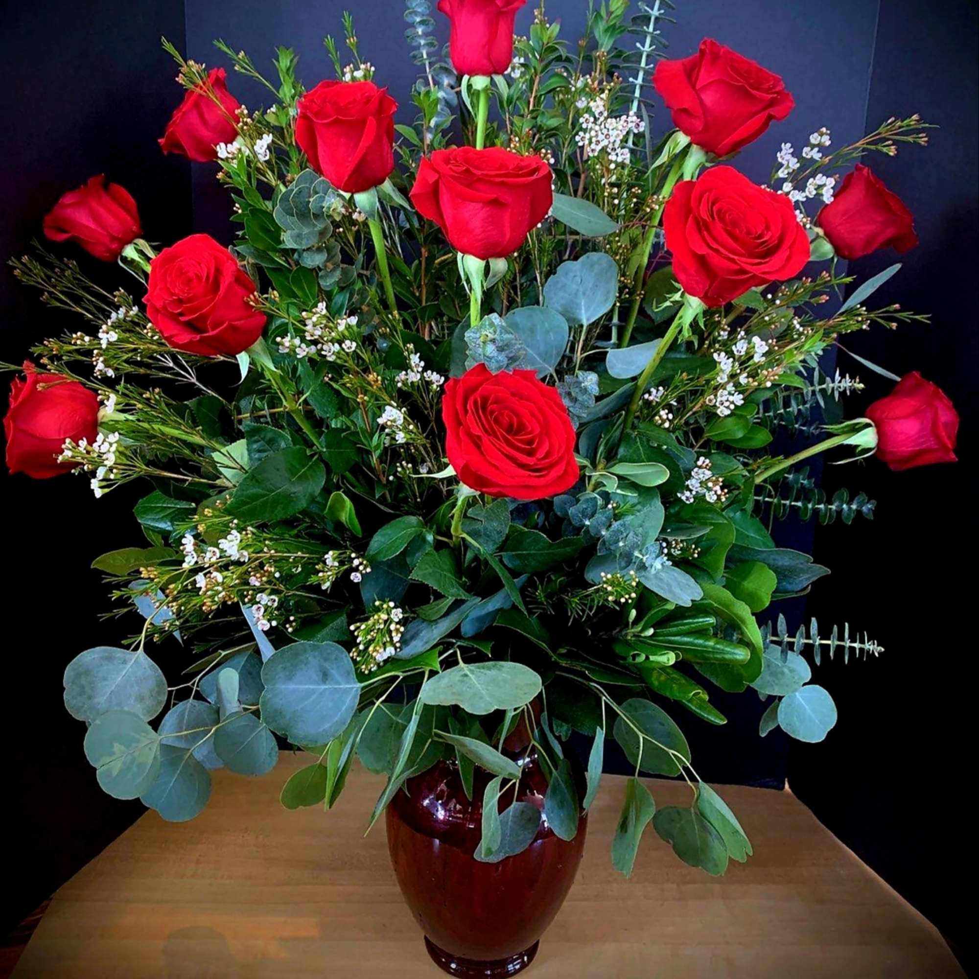 A dozen luscious red roses in a  ruby red glass vase