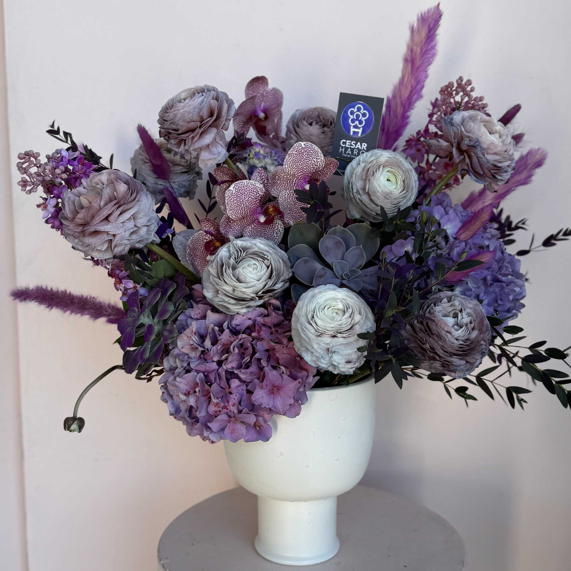 White Compote vase beautifully adorned with succulents, different shades of violet and