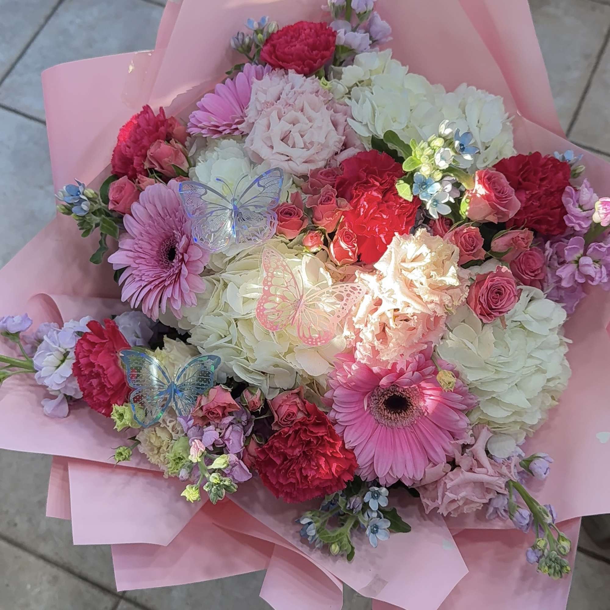 This lush hand-tied arrangement features a romantic blend of blush and hot