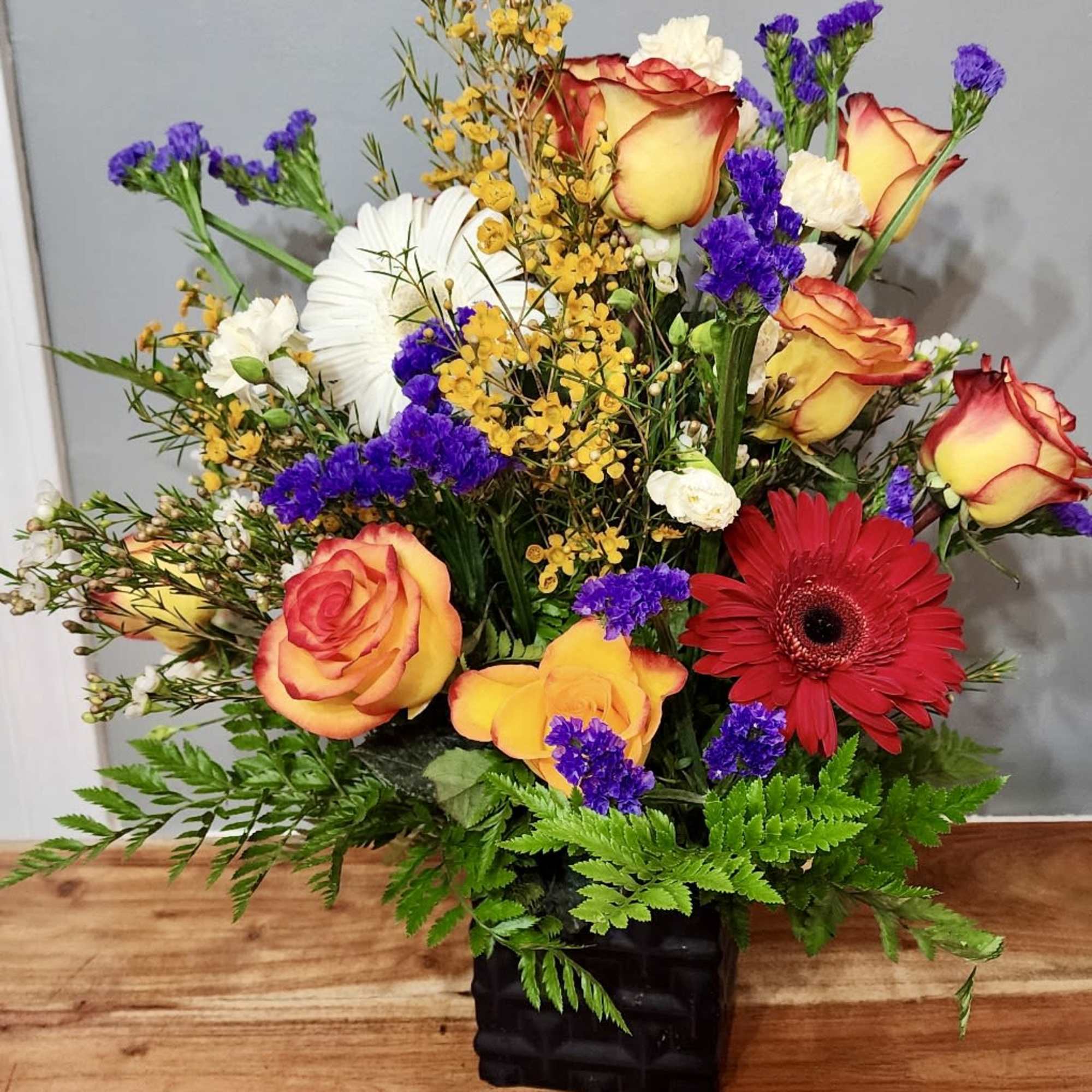Orange fire and ice roses and yellow gerbera daisies in a vase.