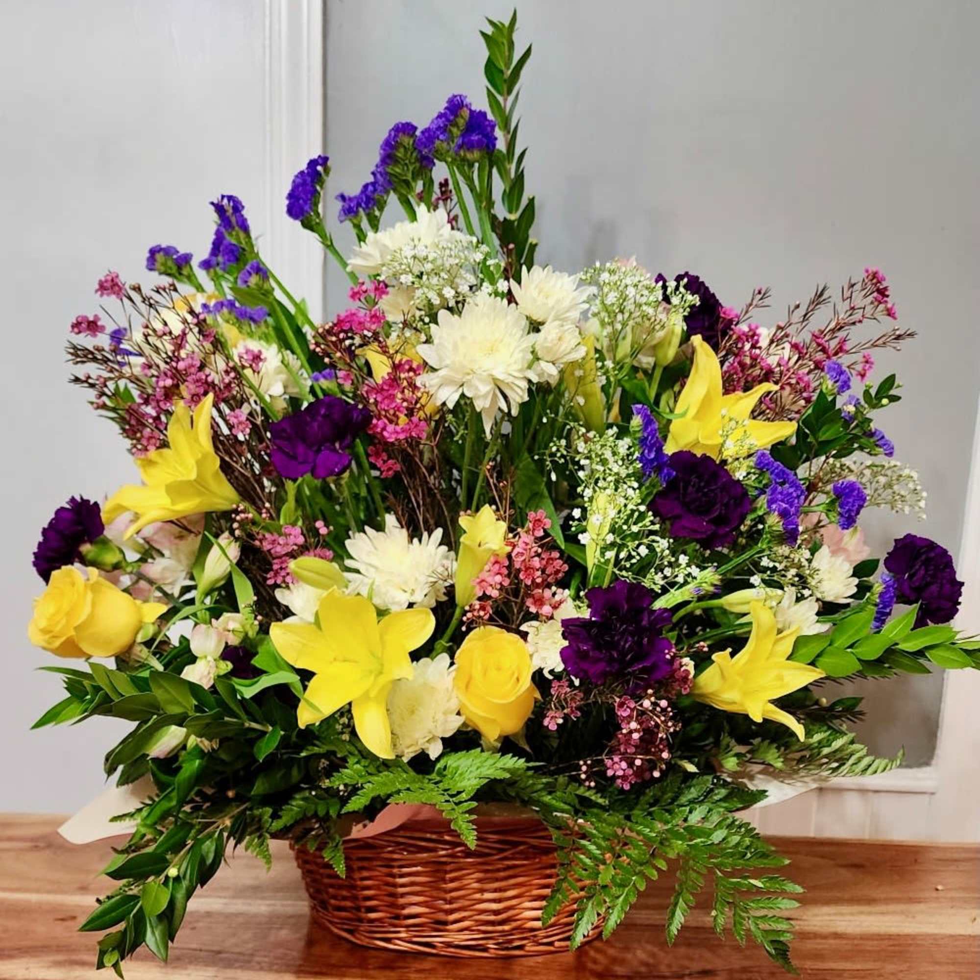 Peach roses with yellow lillies in and charming basket