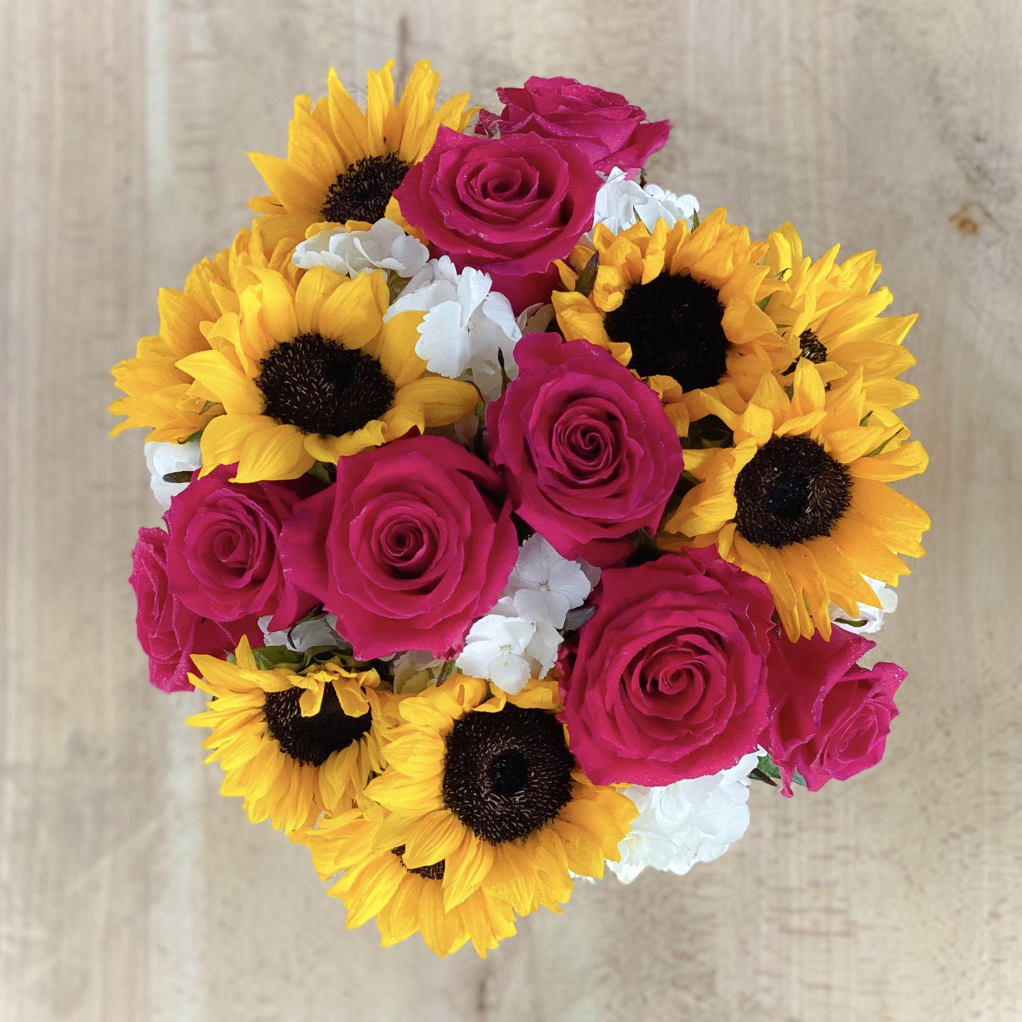 Precious pink roses and exotic sunflowers designed on a bed of luscious