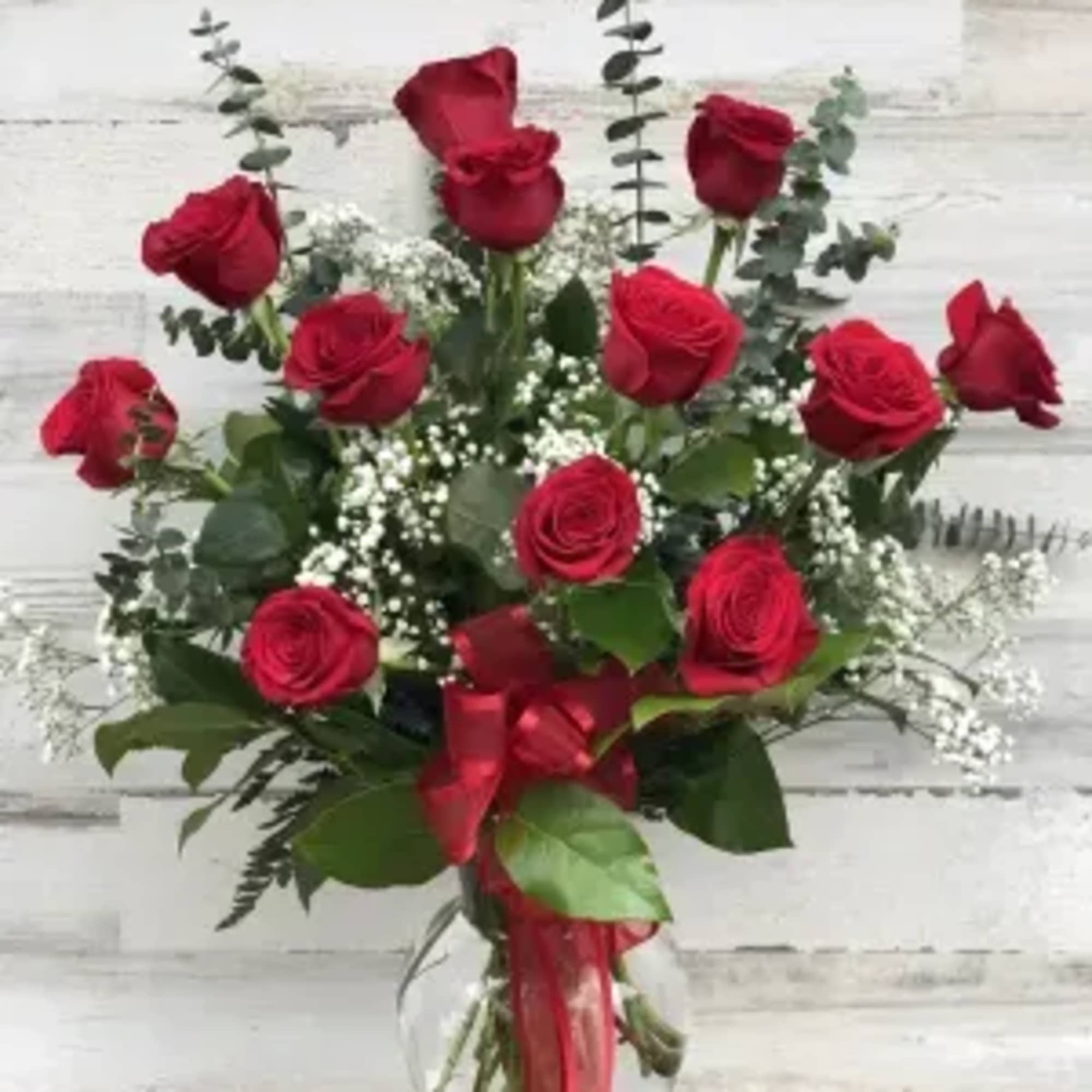 This Classic red  roses  arranged in a red or clear