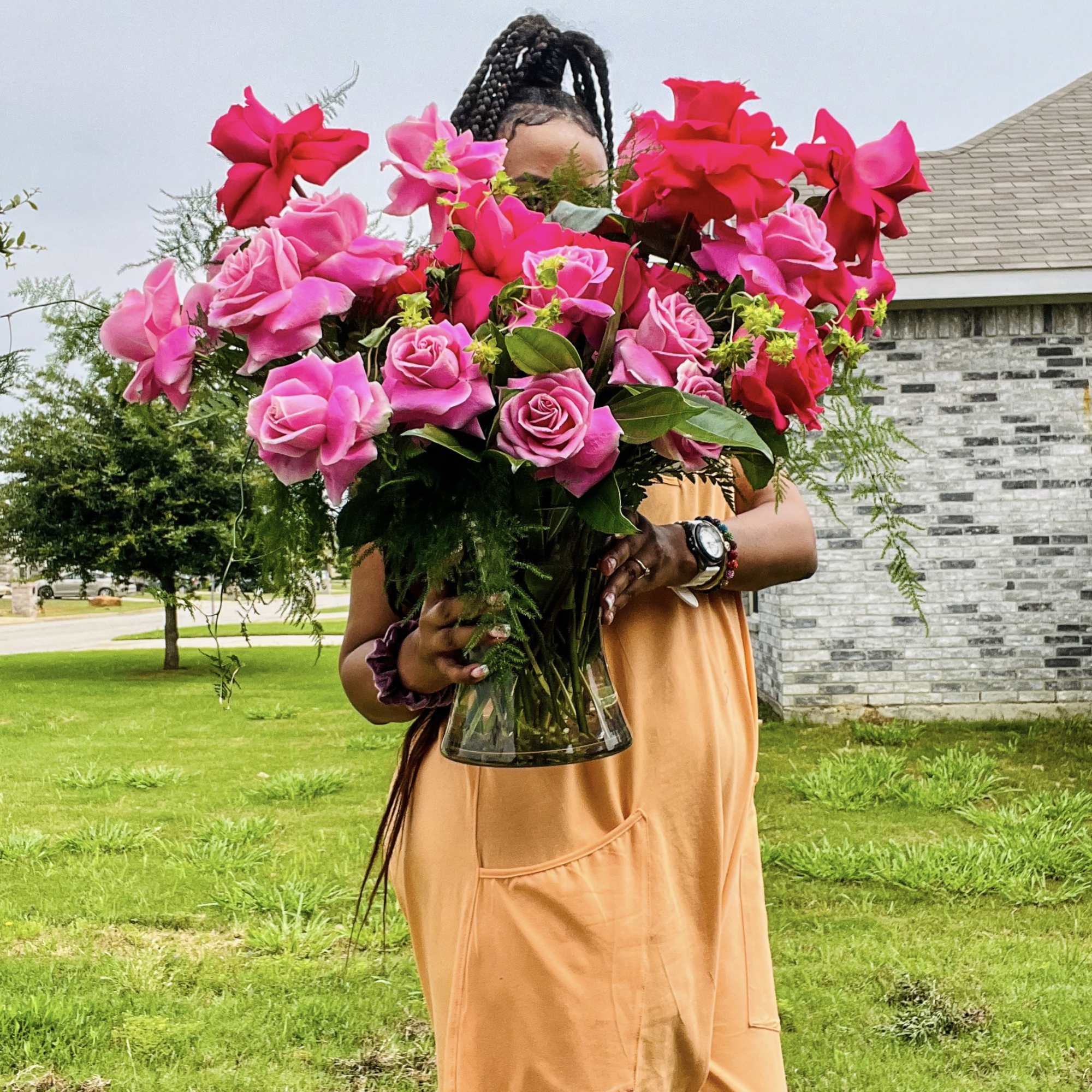 Different shades Premium Roses designed with greenery in clear vase.