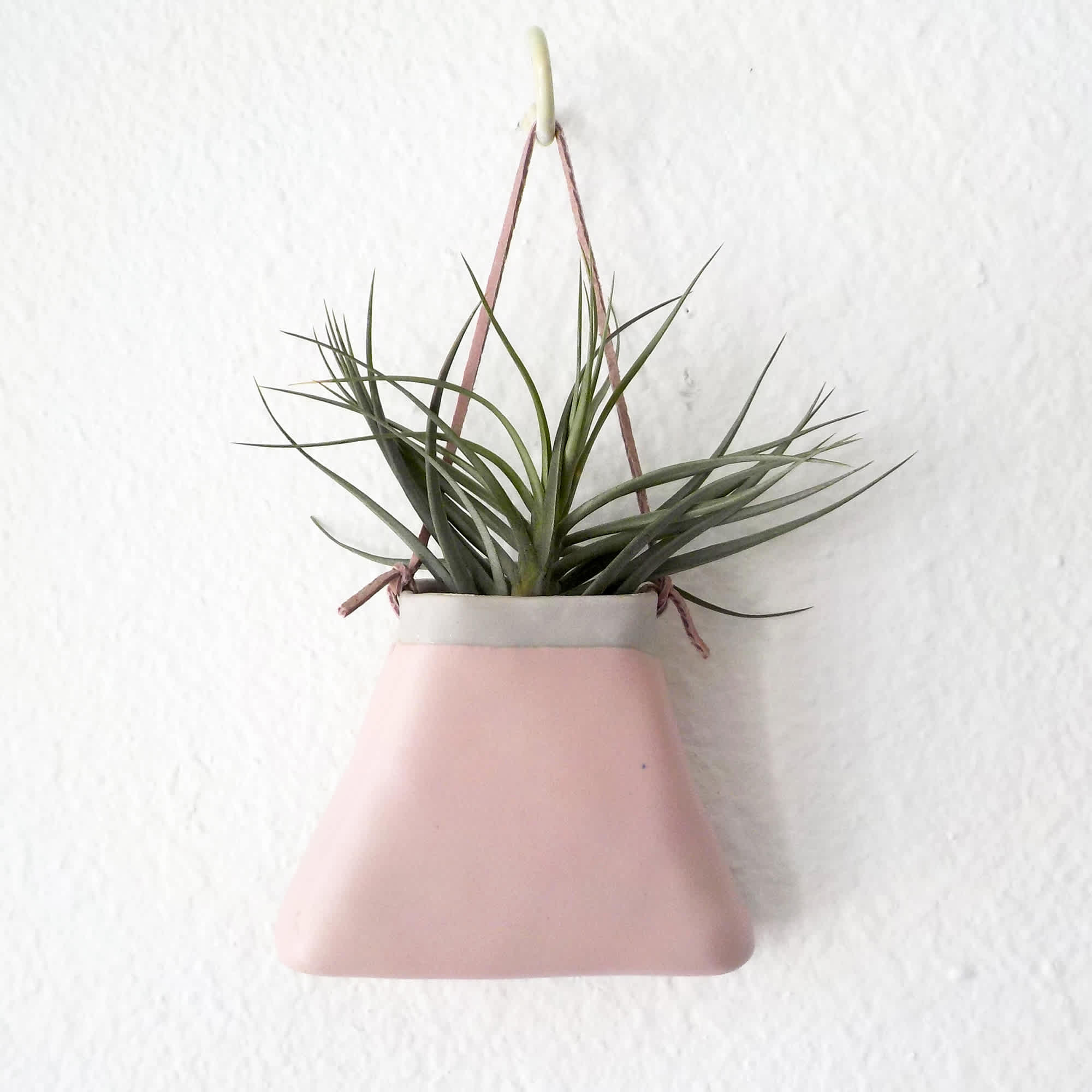 A ceramic triangular "purse" planter with matte pink glaze with a tan
