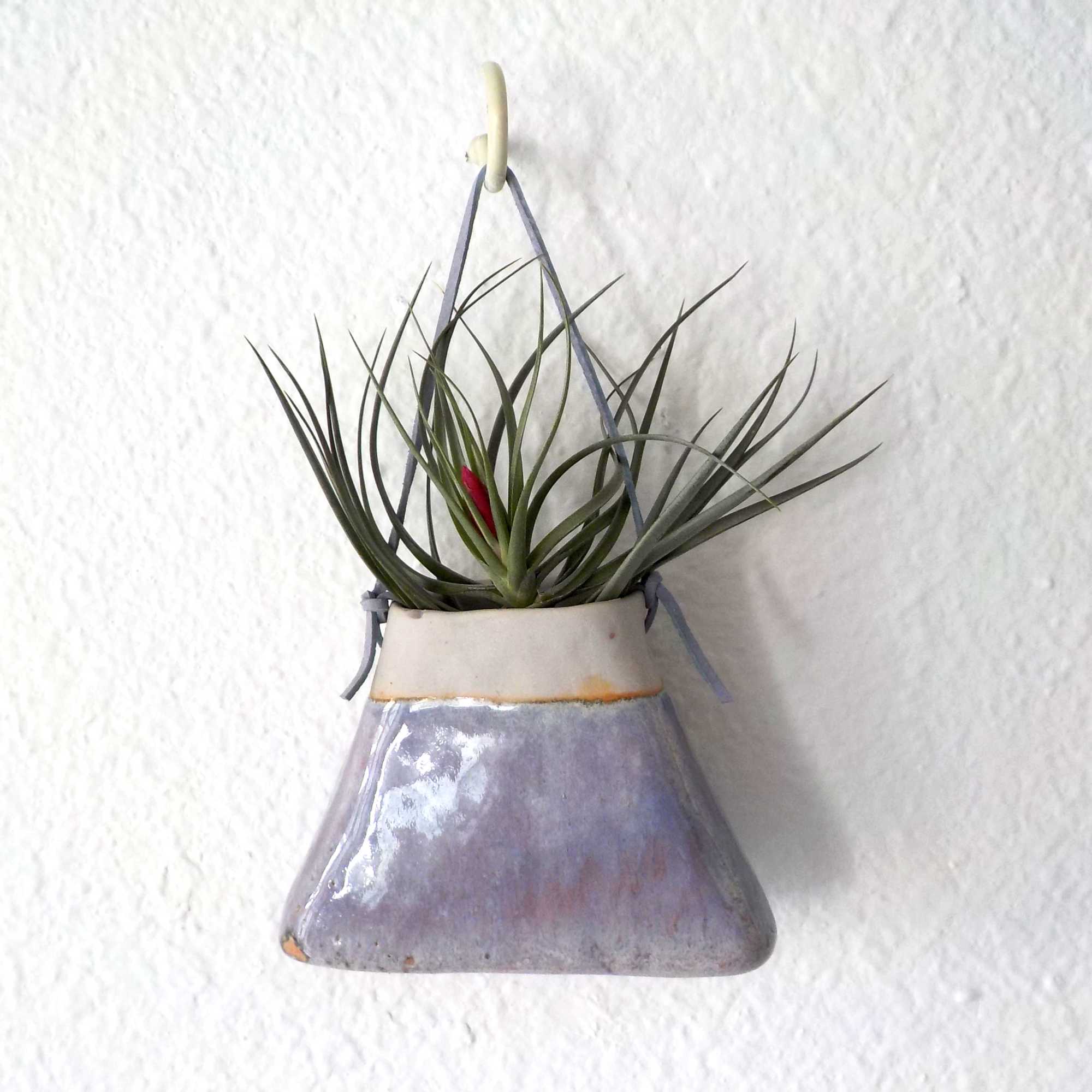 A handmade ceramic triangular "purse" planter with matte pink glaze with a