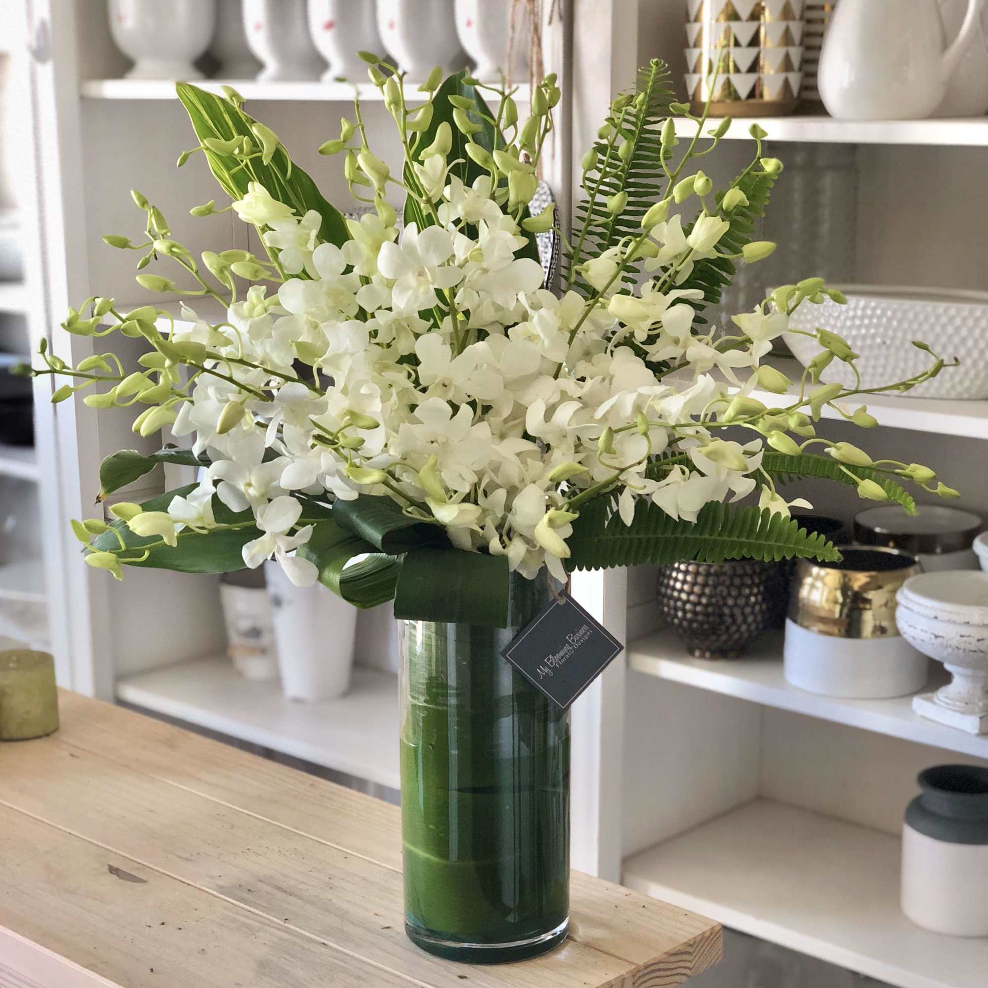 White Orchids in tall clear cylinder vase with a tea leaf lining.