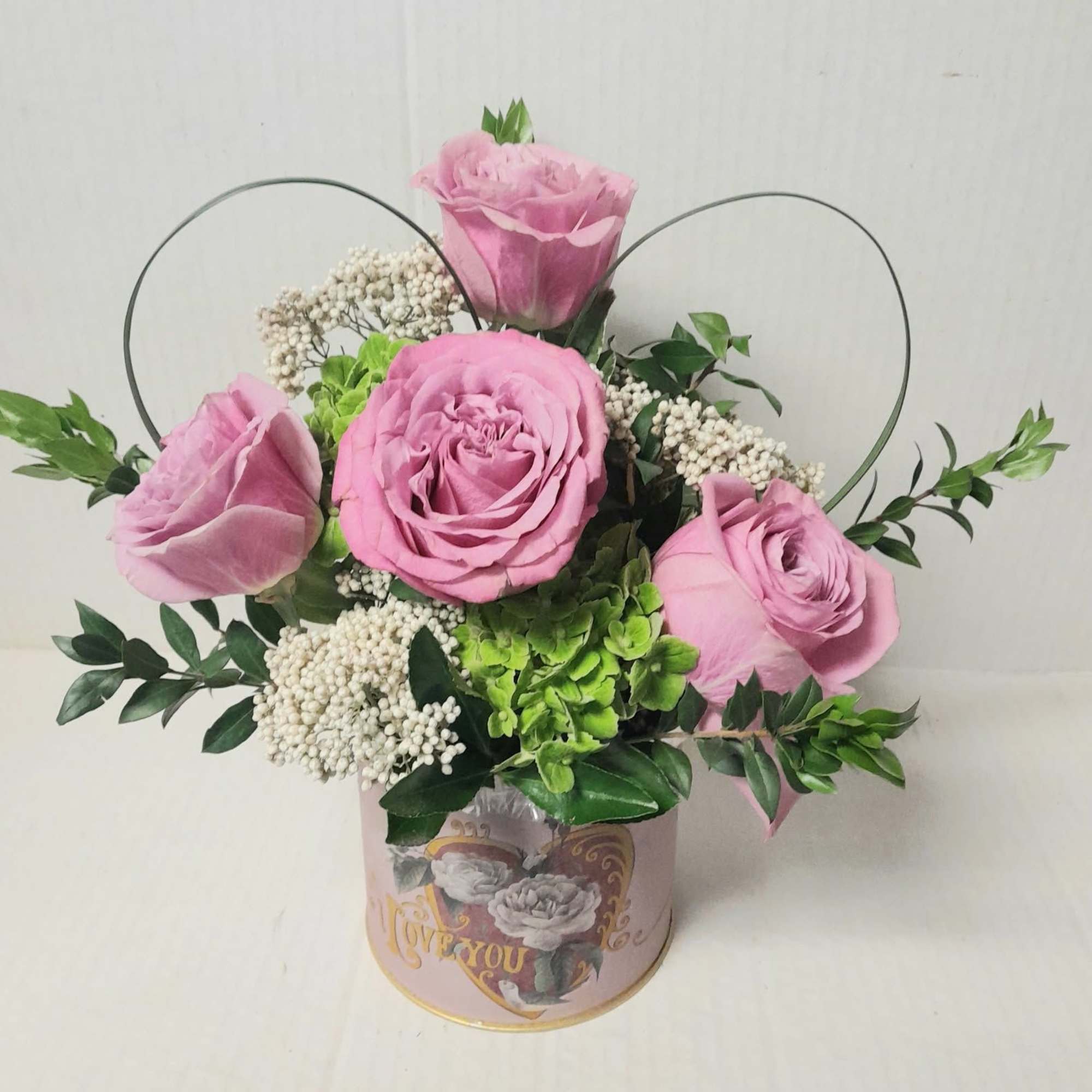A special keepsake container holds roses, hydrangeas, and rice flower with a
