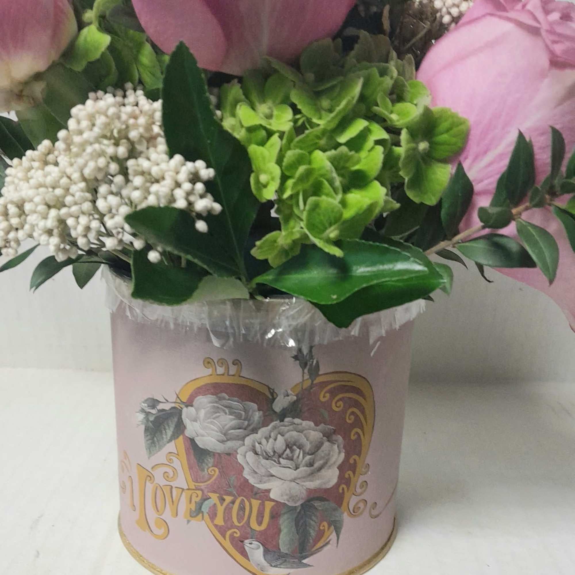 A special keepsake container holds roses, hydrangeas, and rice flower with a
