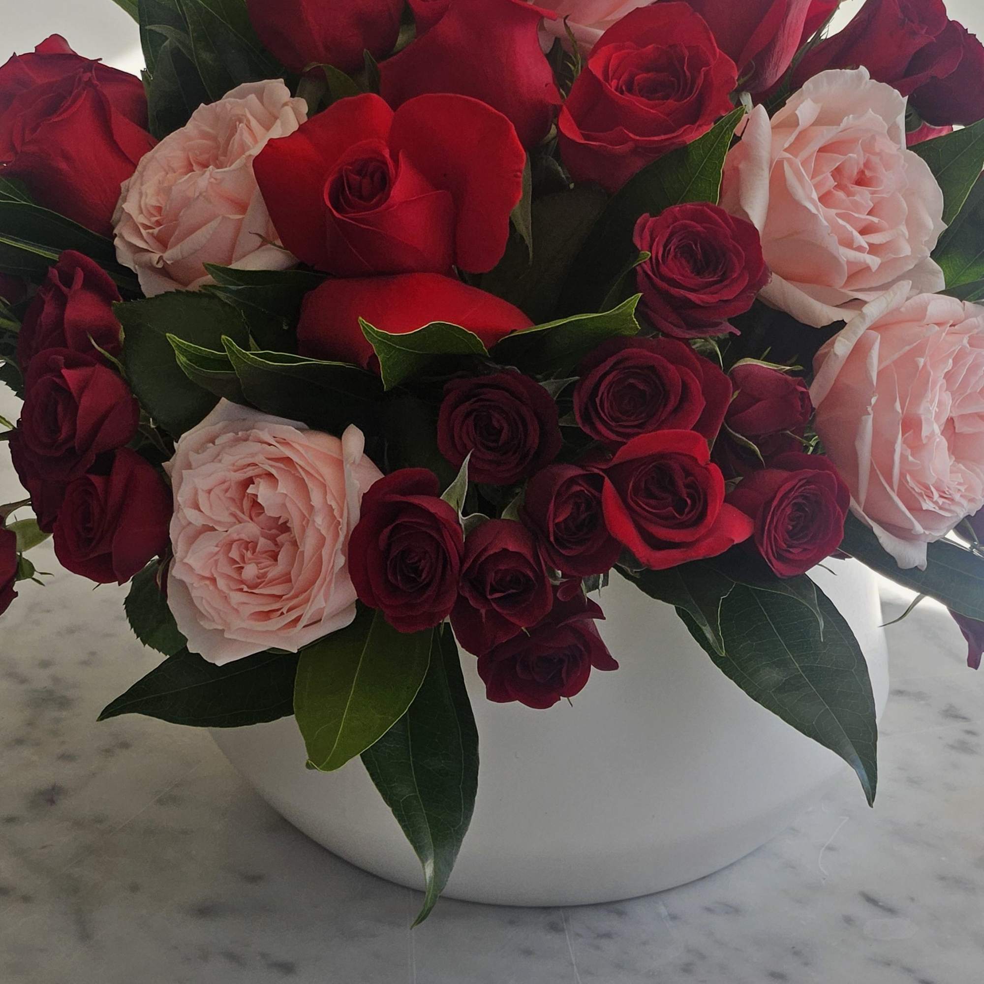 A stunning vase arrangement that includes a Dozen red roses, pink garden