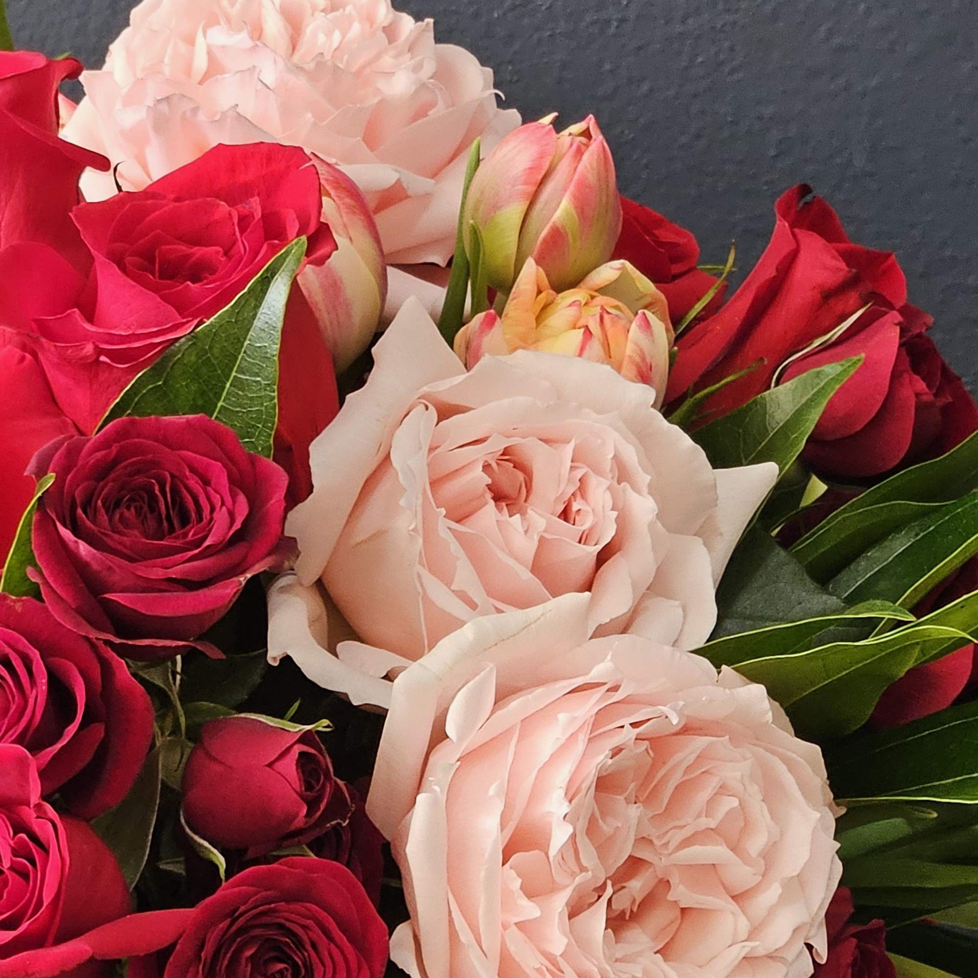 A stunning vase arrangement that includes a Dozen red roses, pink garden