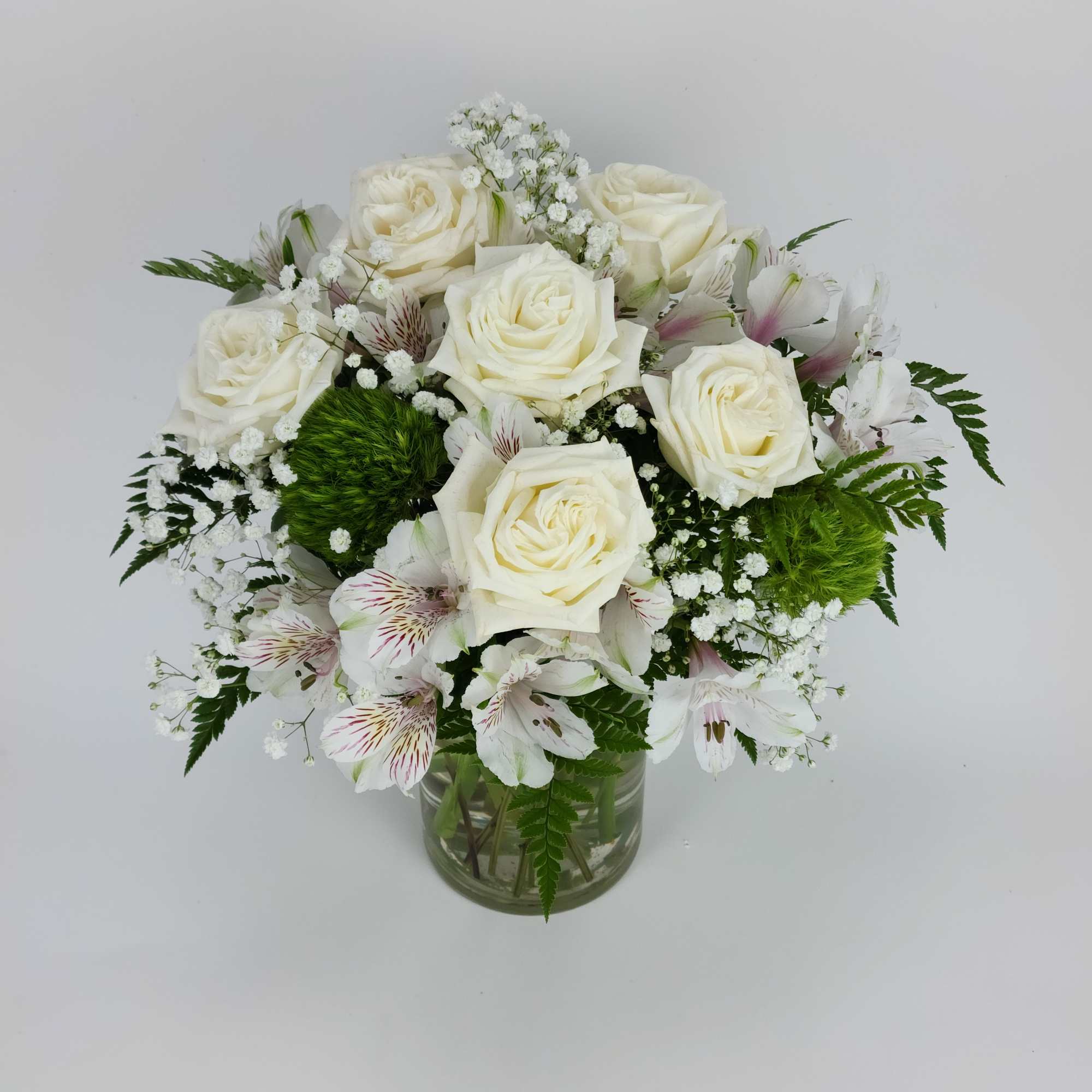 A small arrangement with roses, alstroemerias, dianthus, fillers, and greenery in a