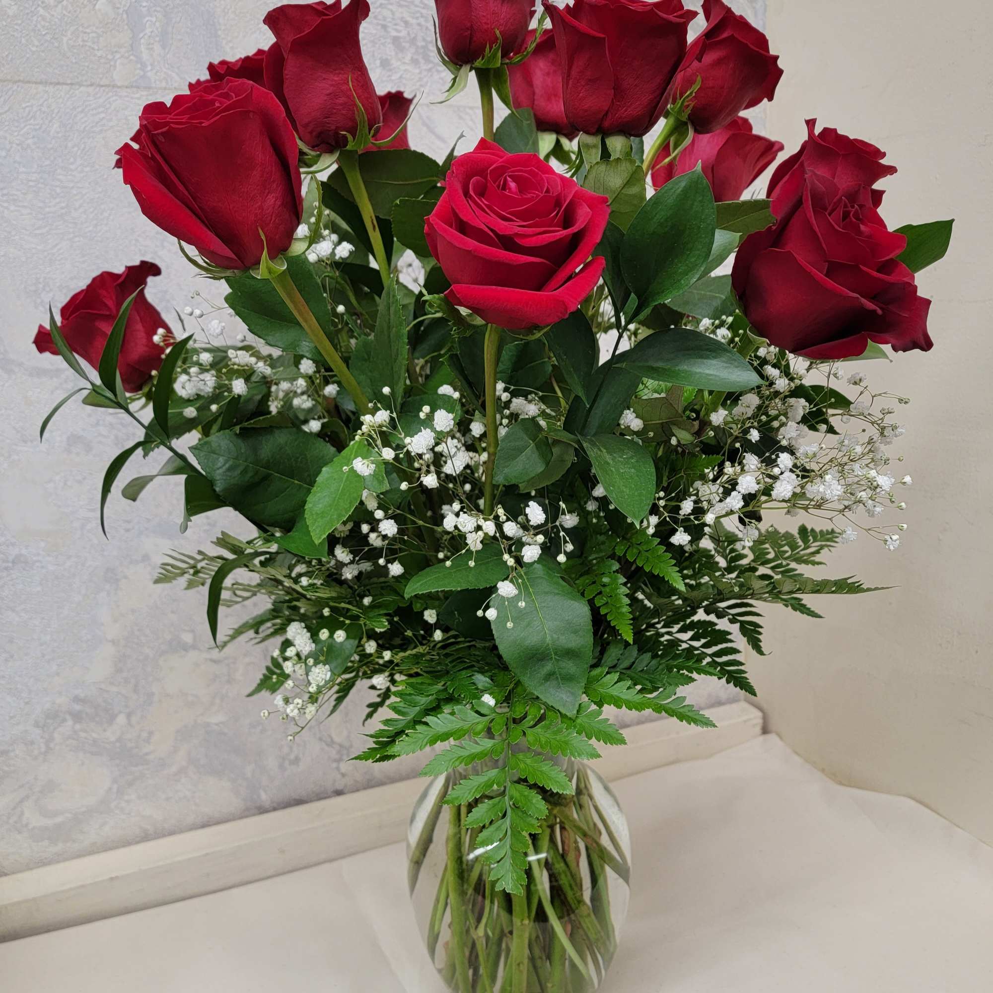 18 premium red roses arranged in a large vase with greens and