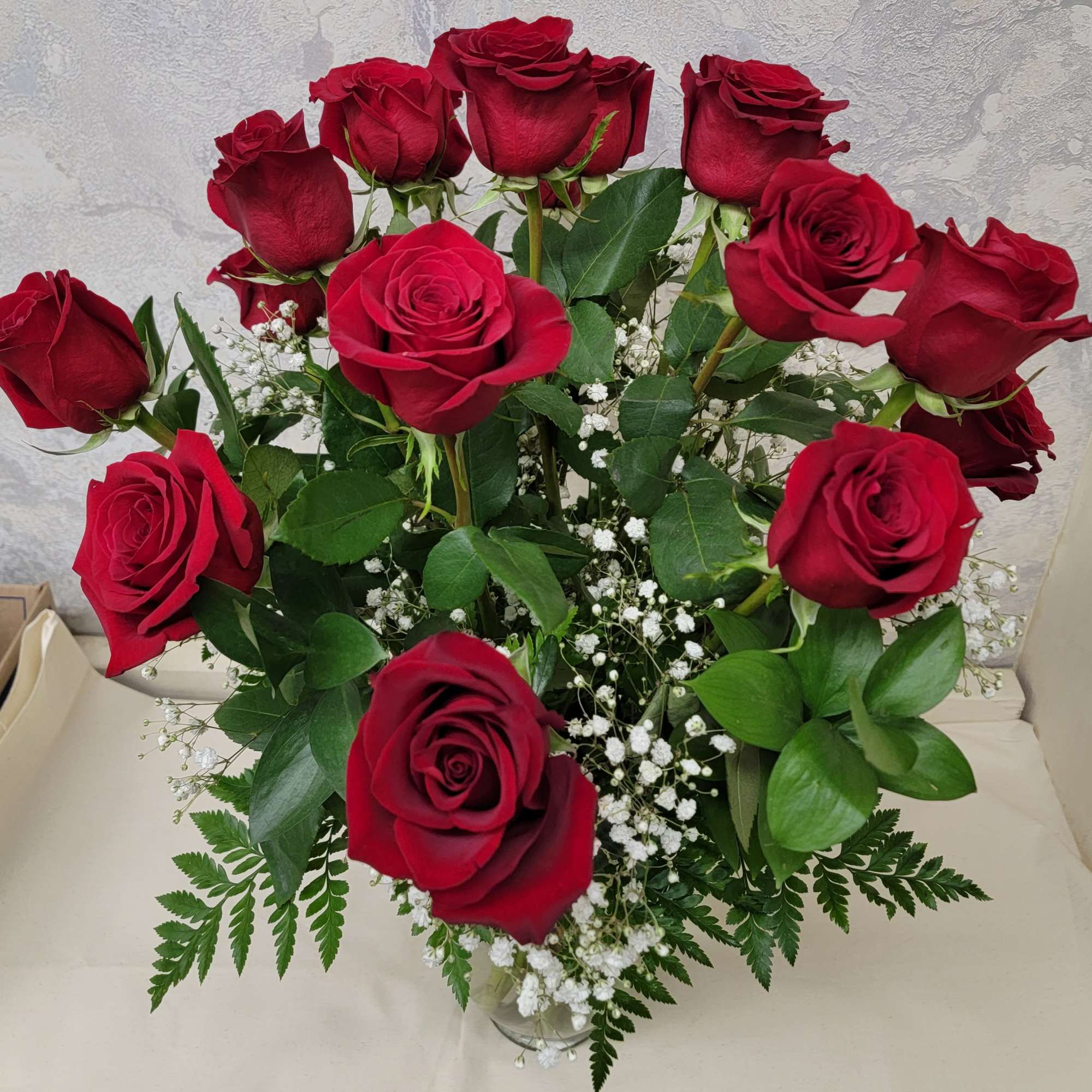 18 premium red roses arranged in a large vase with greens and