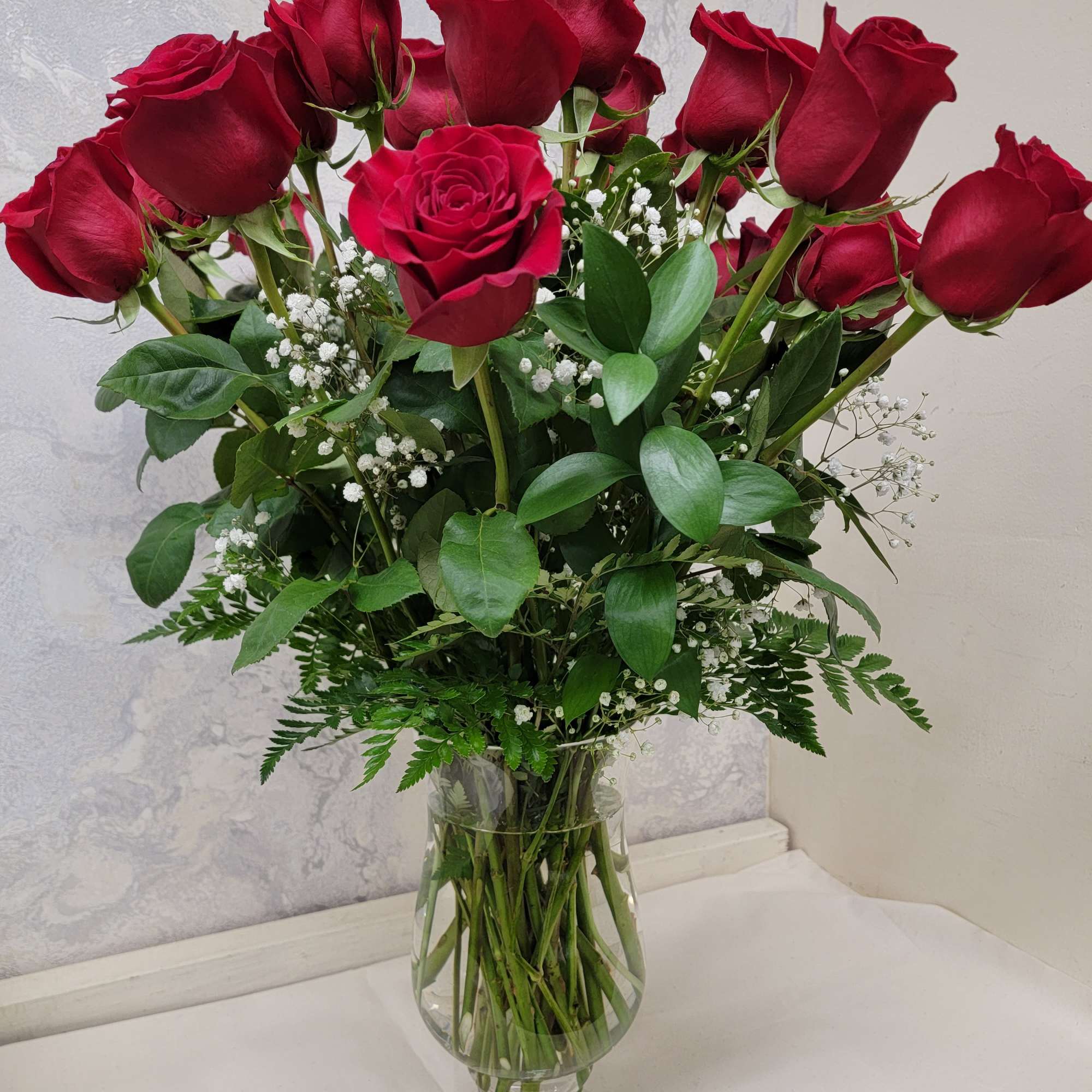 An impressive presentation of two dozen long-stemmed red roses accented with a