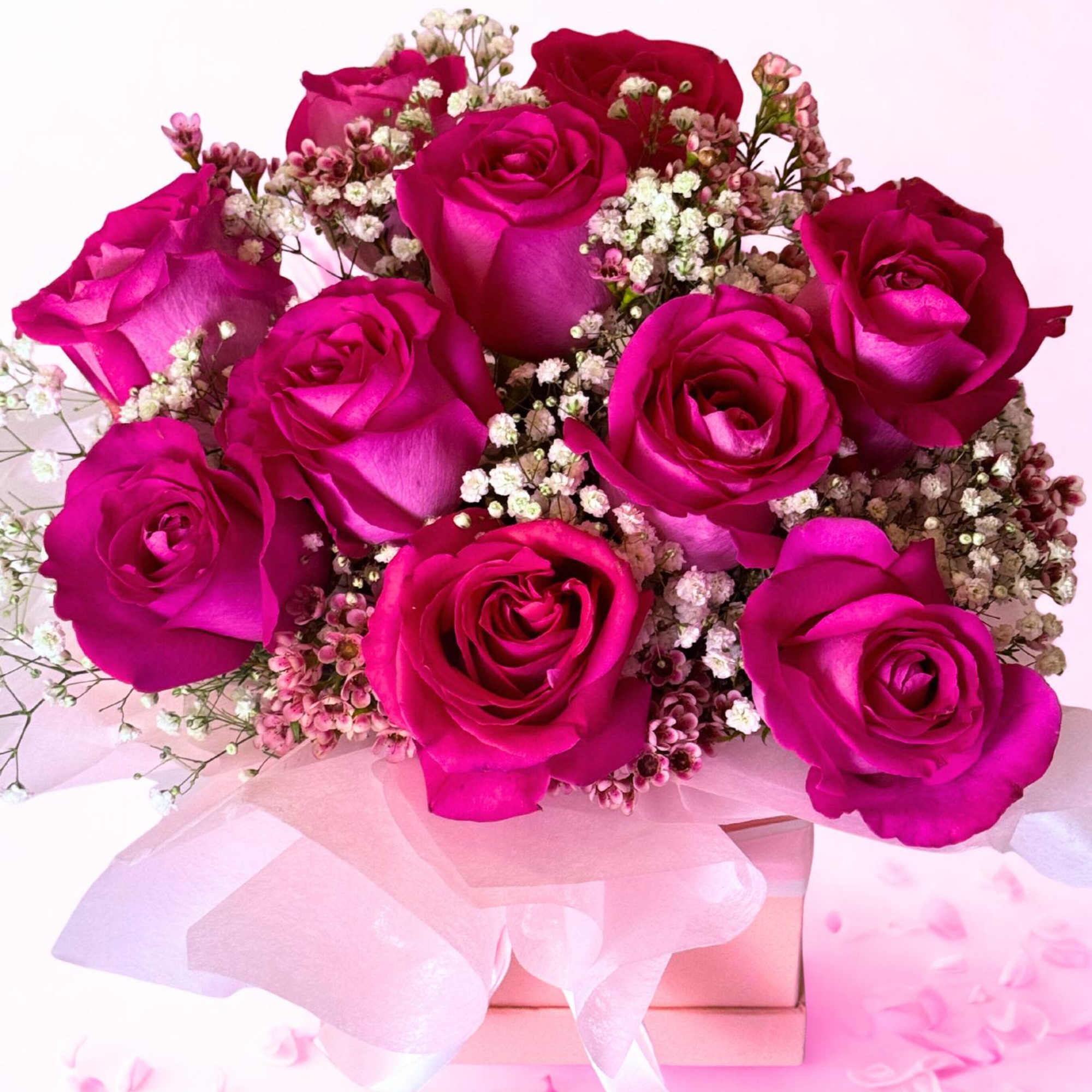 At the center is a lush bouquet of one dozen pink roses