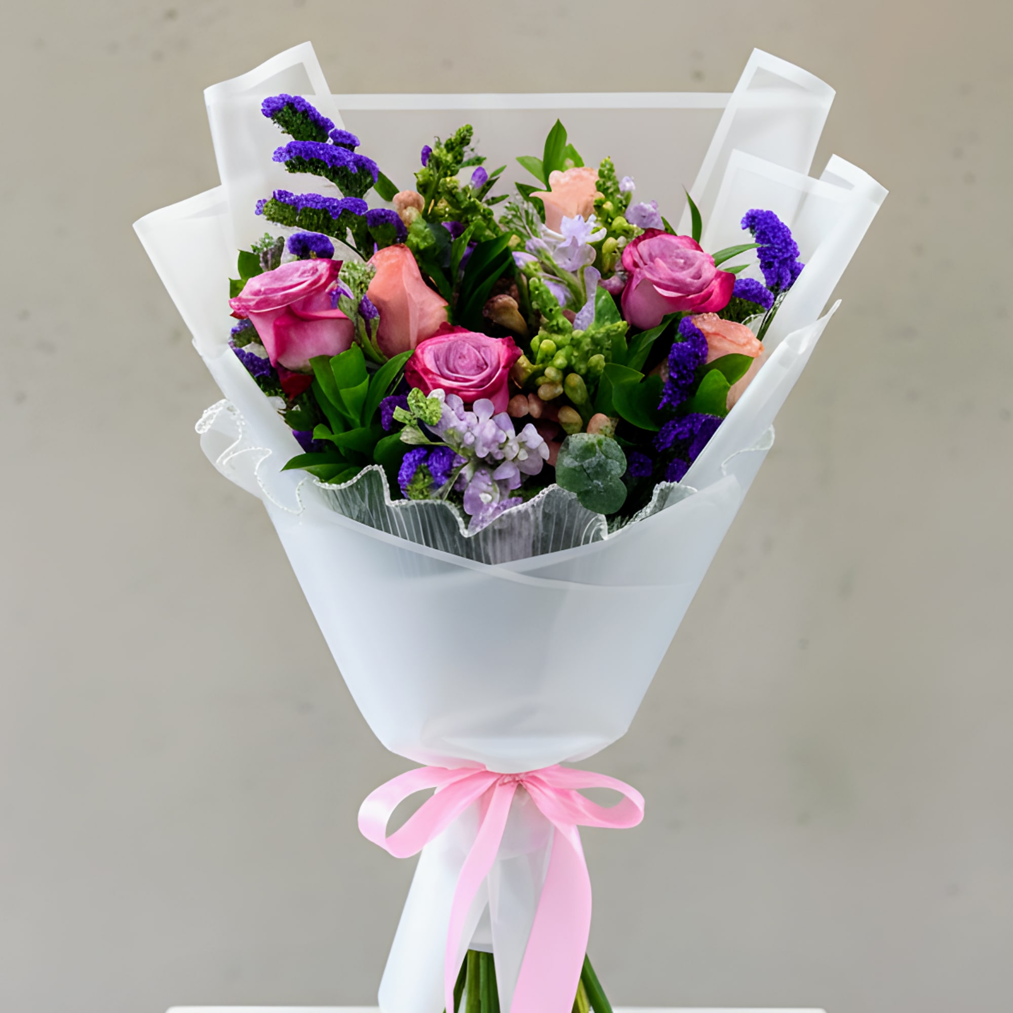 A fresh floral blend of roses and seasonal flowers in pink, purple