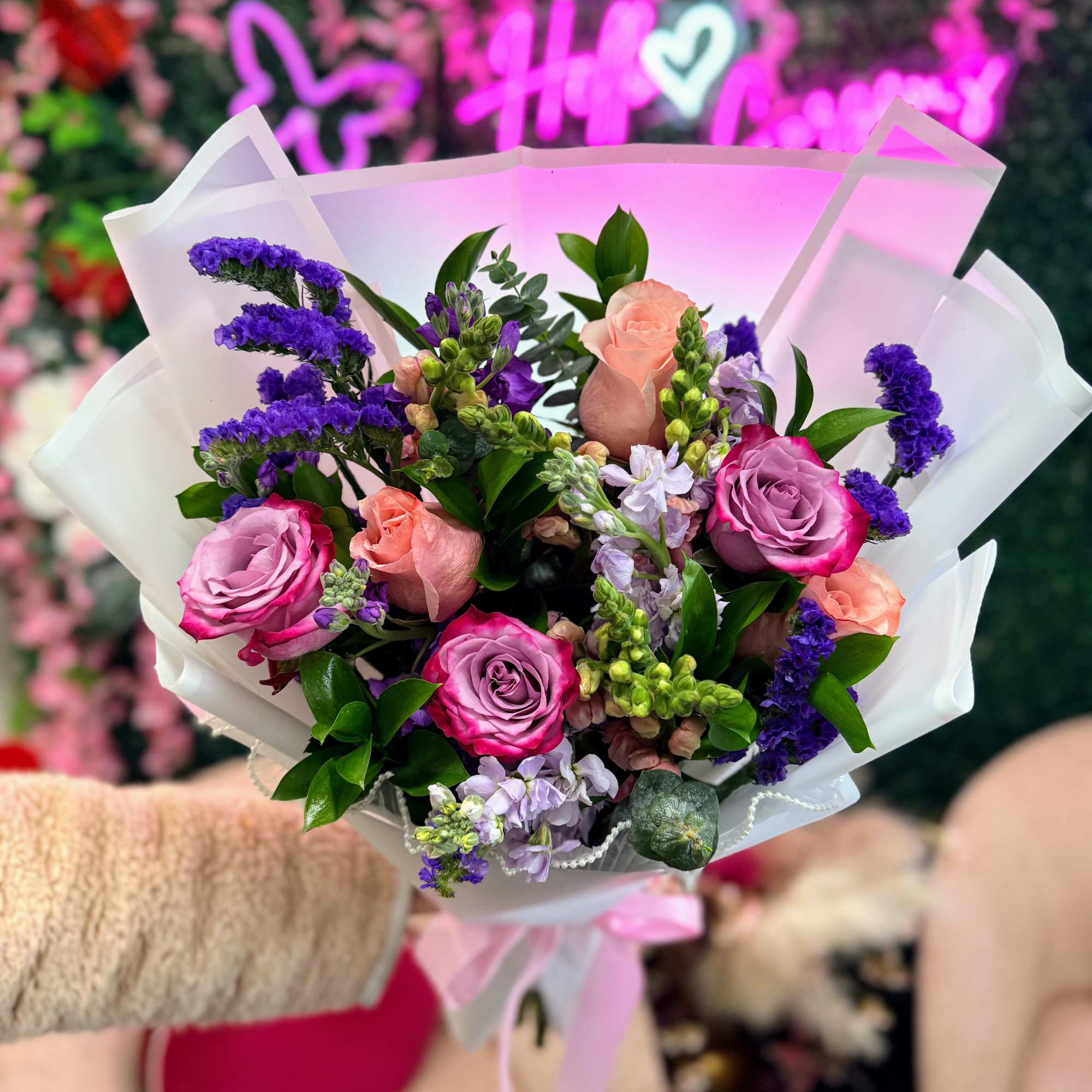 A fresh floral blend of roses and seasonal flowers in pink, purple