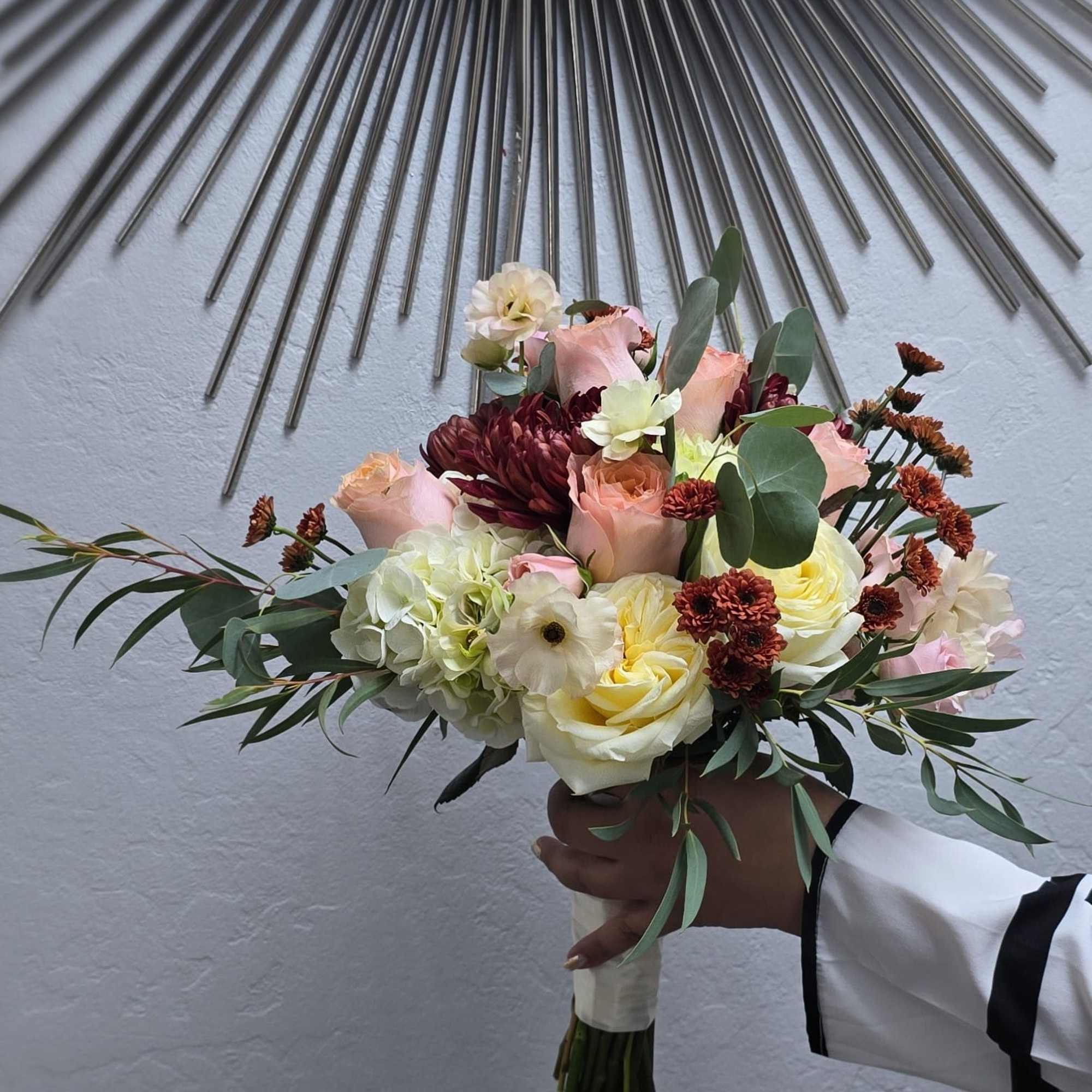 A romantic bridal bouquet designed with soft blush and cream roses, rich