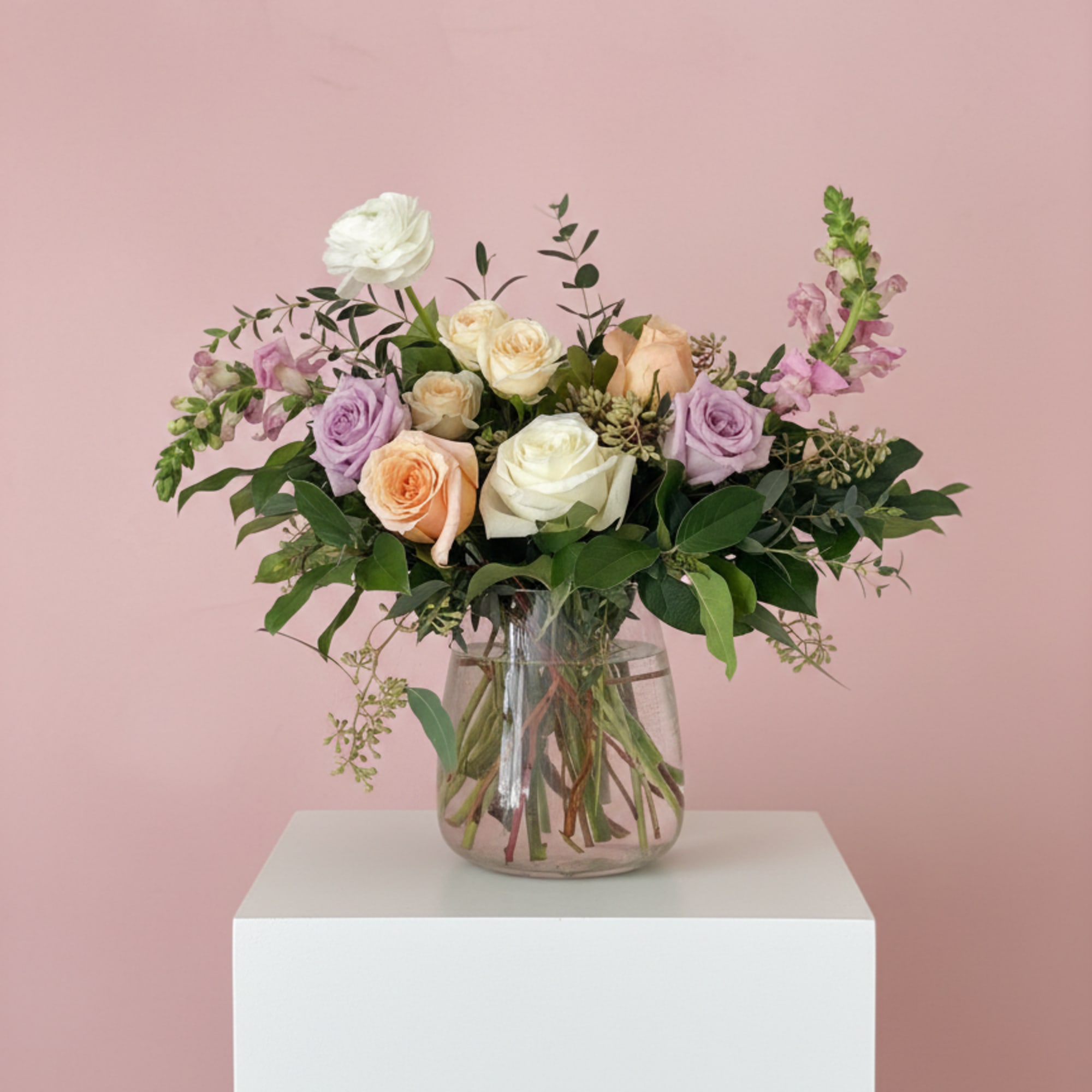 A classic clear vase with beautiful pastel flowers and foliage.