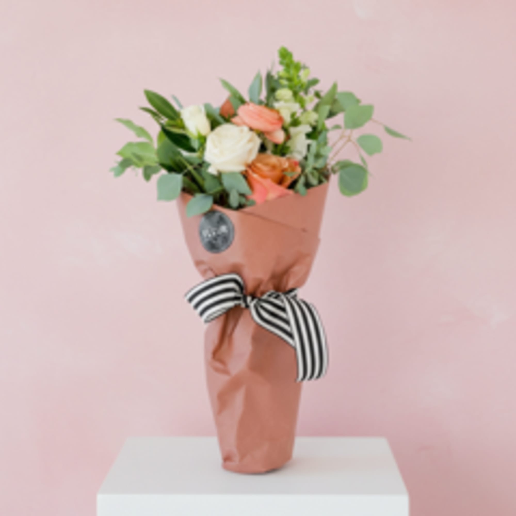 Seasonal blooms and foliage packaged in a couture pink market paper. Includes