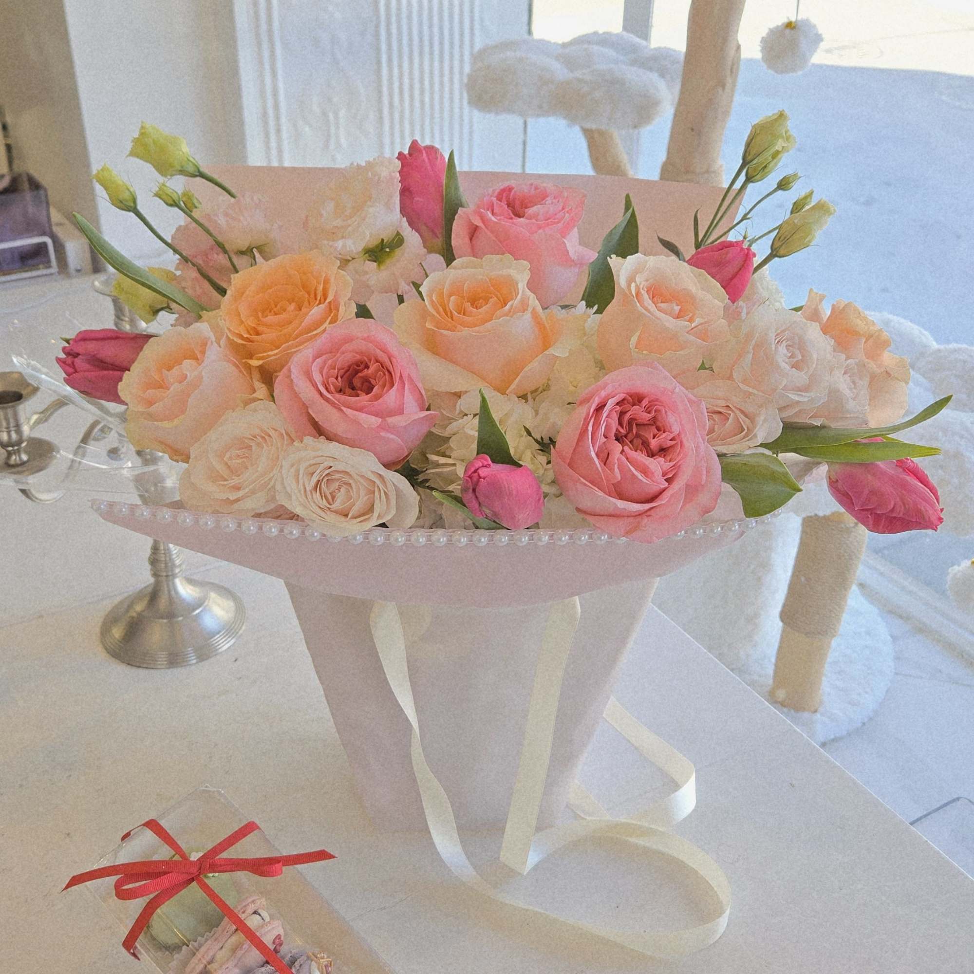 This bouquet features a lush mix of premium roses in blush, peach