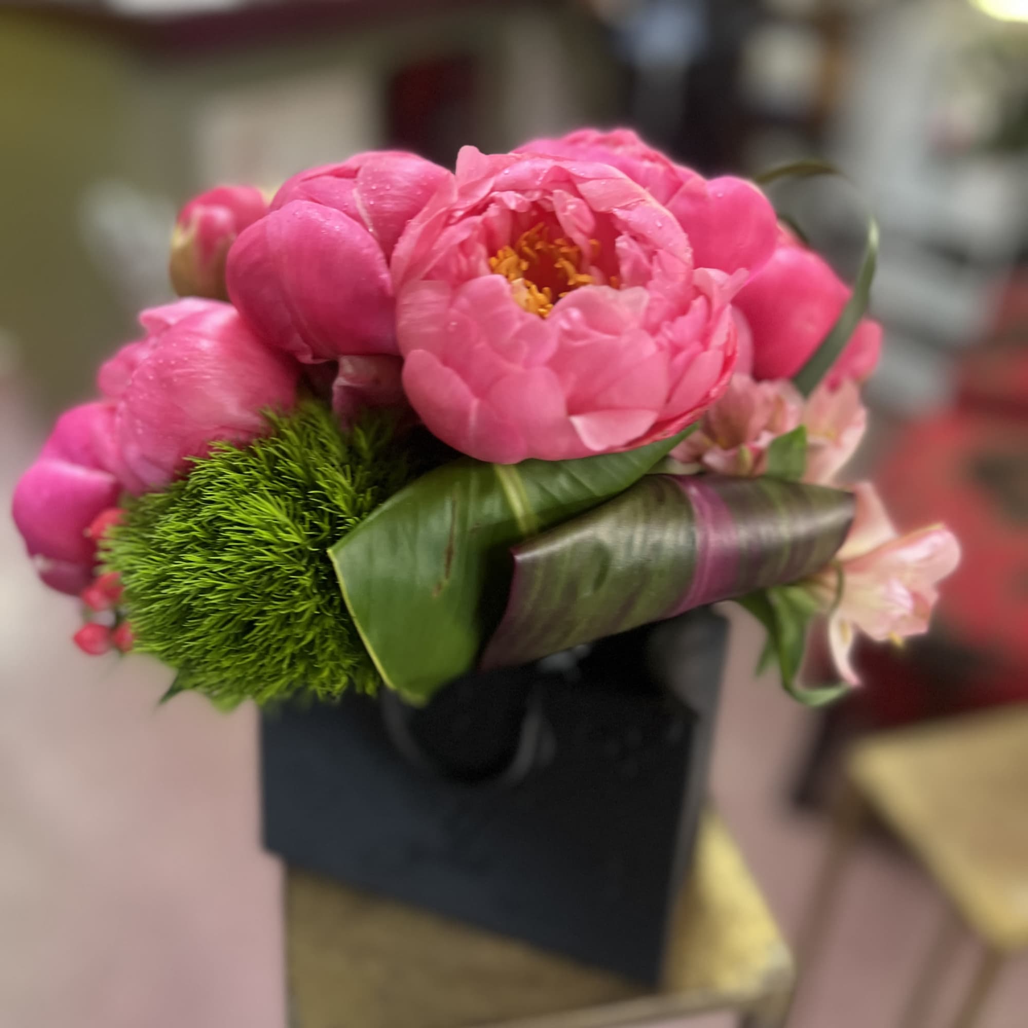 Bundle of peonies in a vase with decorative foliage's and textural elements