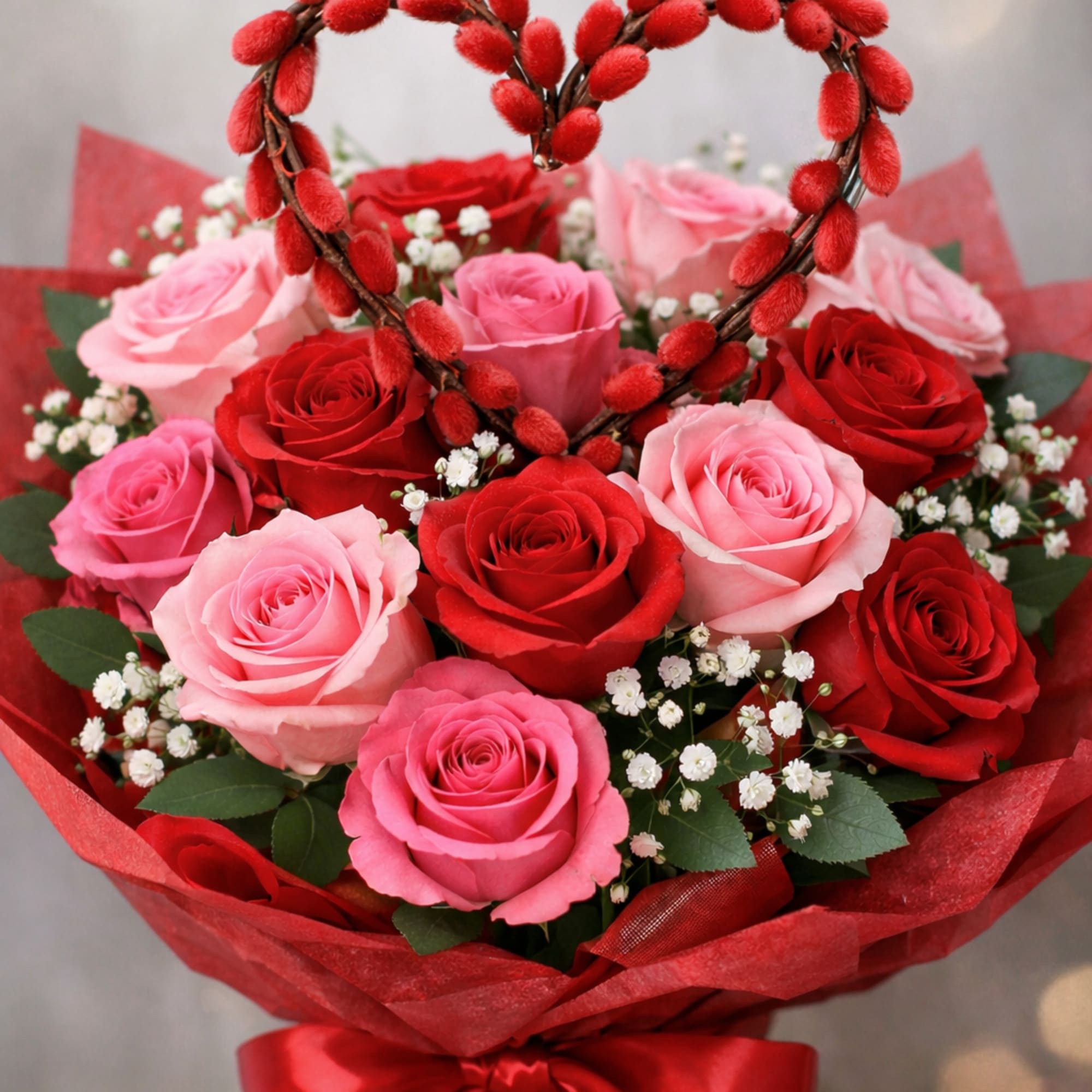 Red and pink roses, babysbreath adorned with a salix heart. Bouquet is