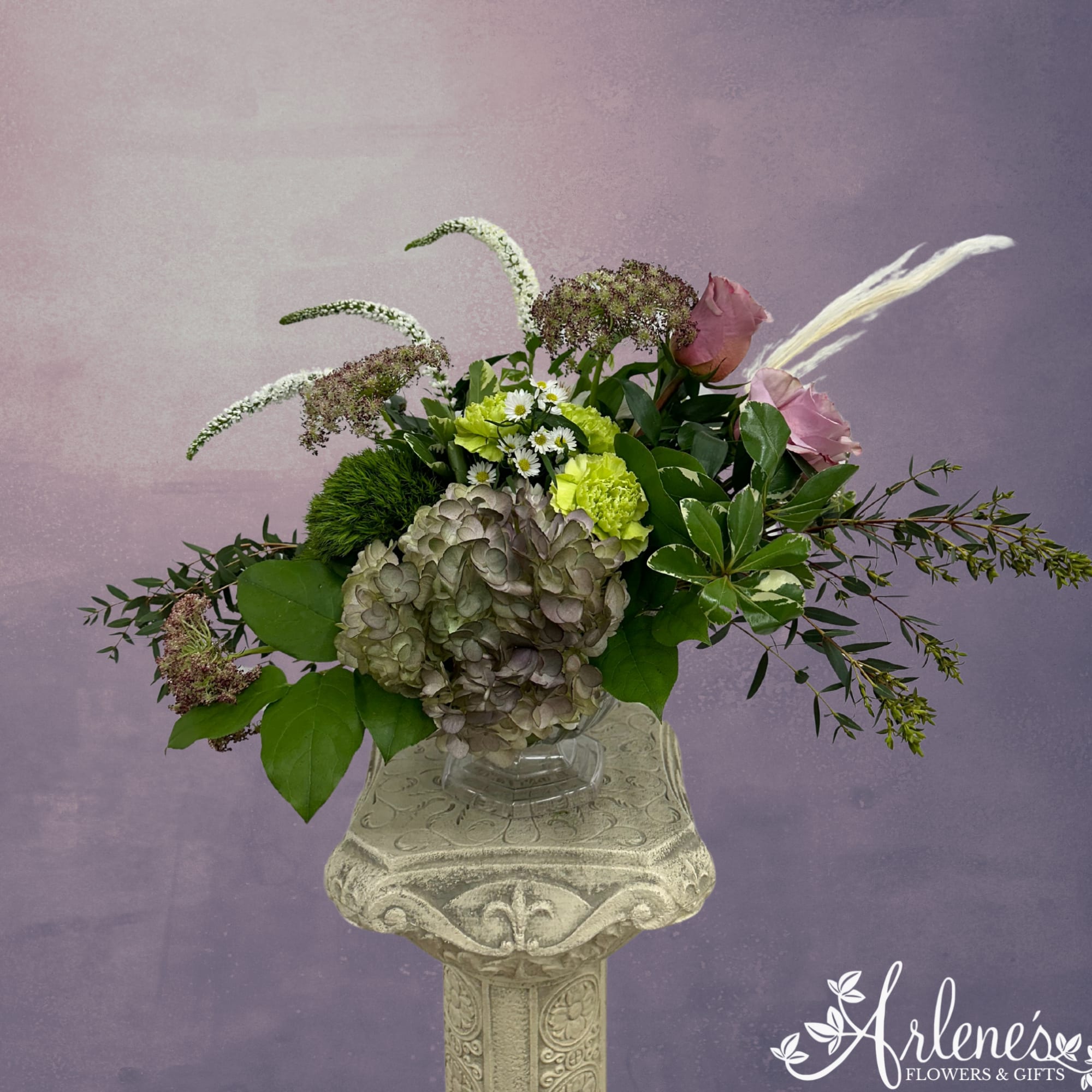Antique hydrangea, dried grasses, veronica, lavender roses and green carnations swirl around