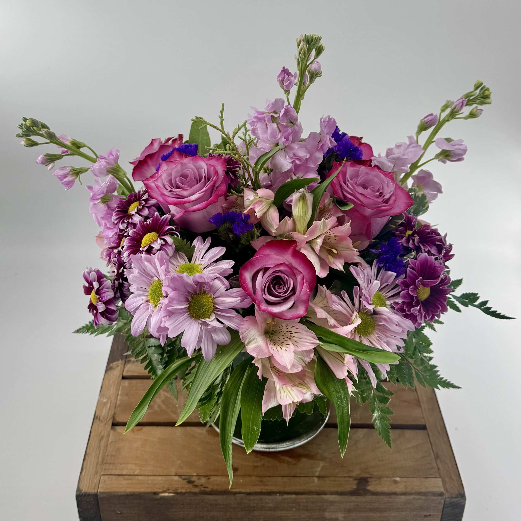 This ethereal floral arrangement mesmerizes with a serene blend of purples, featuring