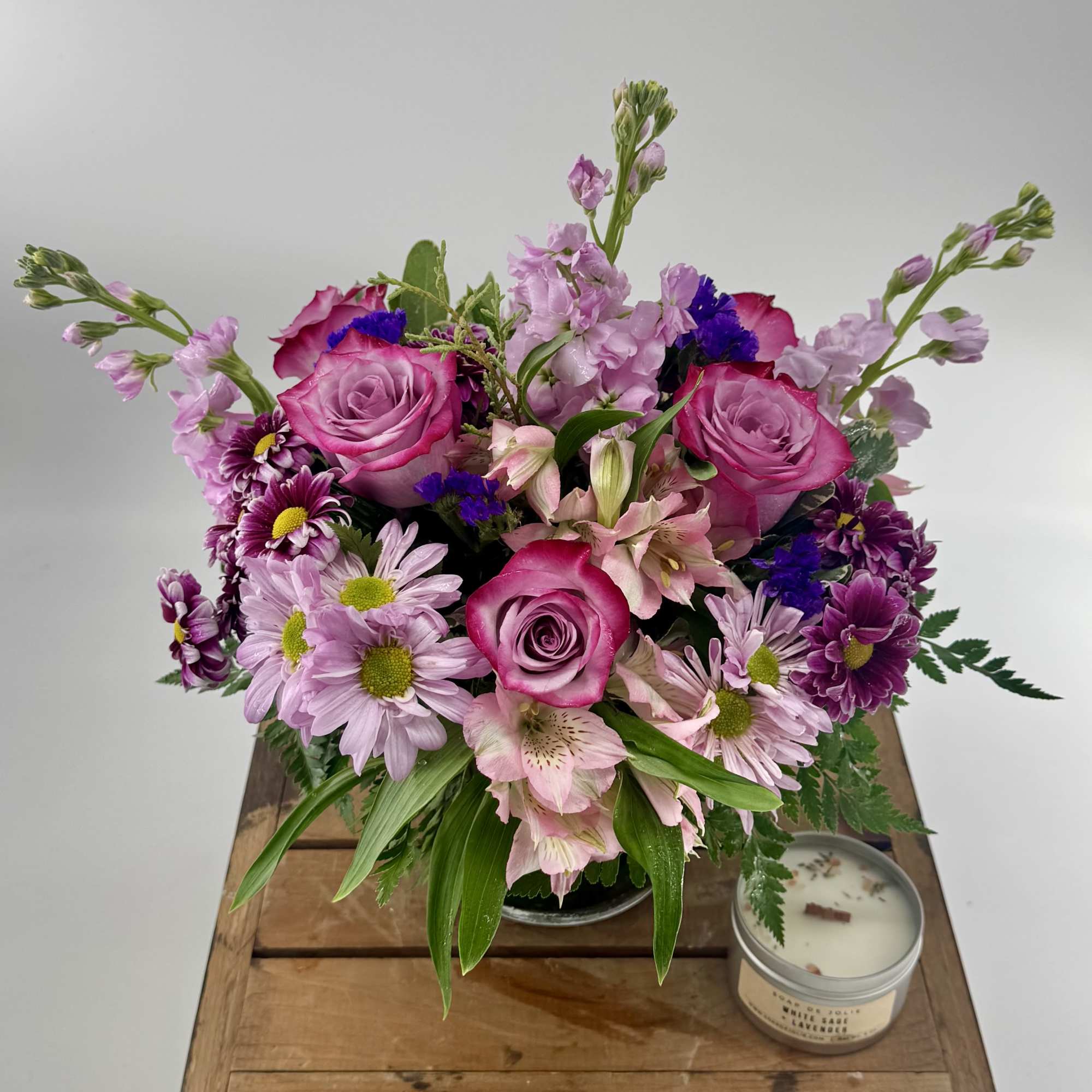 This ethereal floral arrangement mesmerizes with a serene blend of purples, featuring