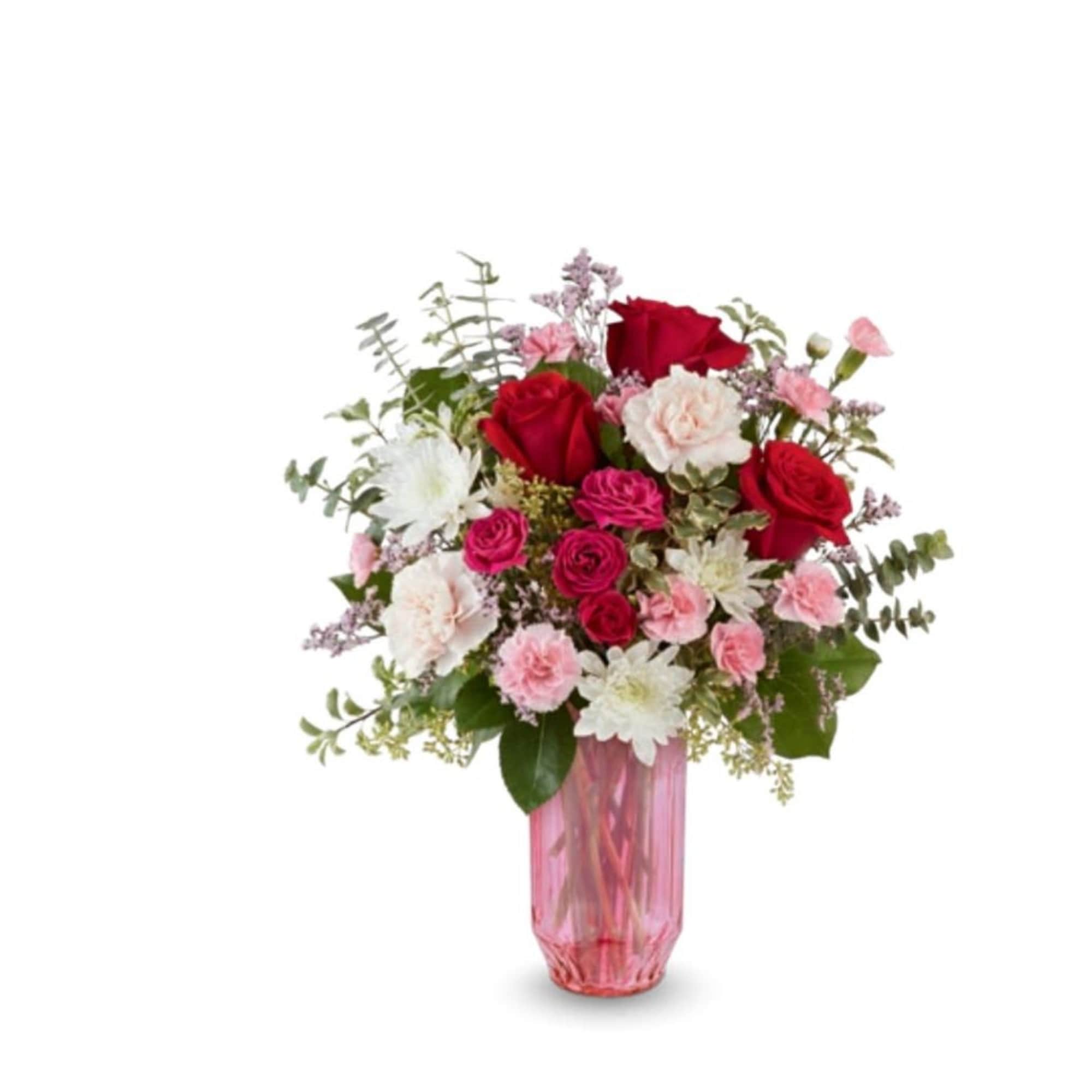 This pink vase holds a variety of flowers and colors, red roses