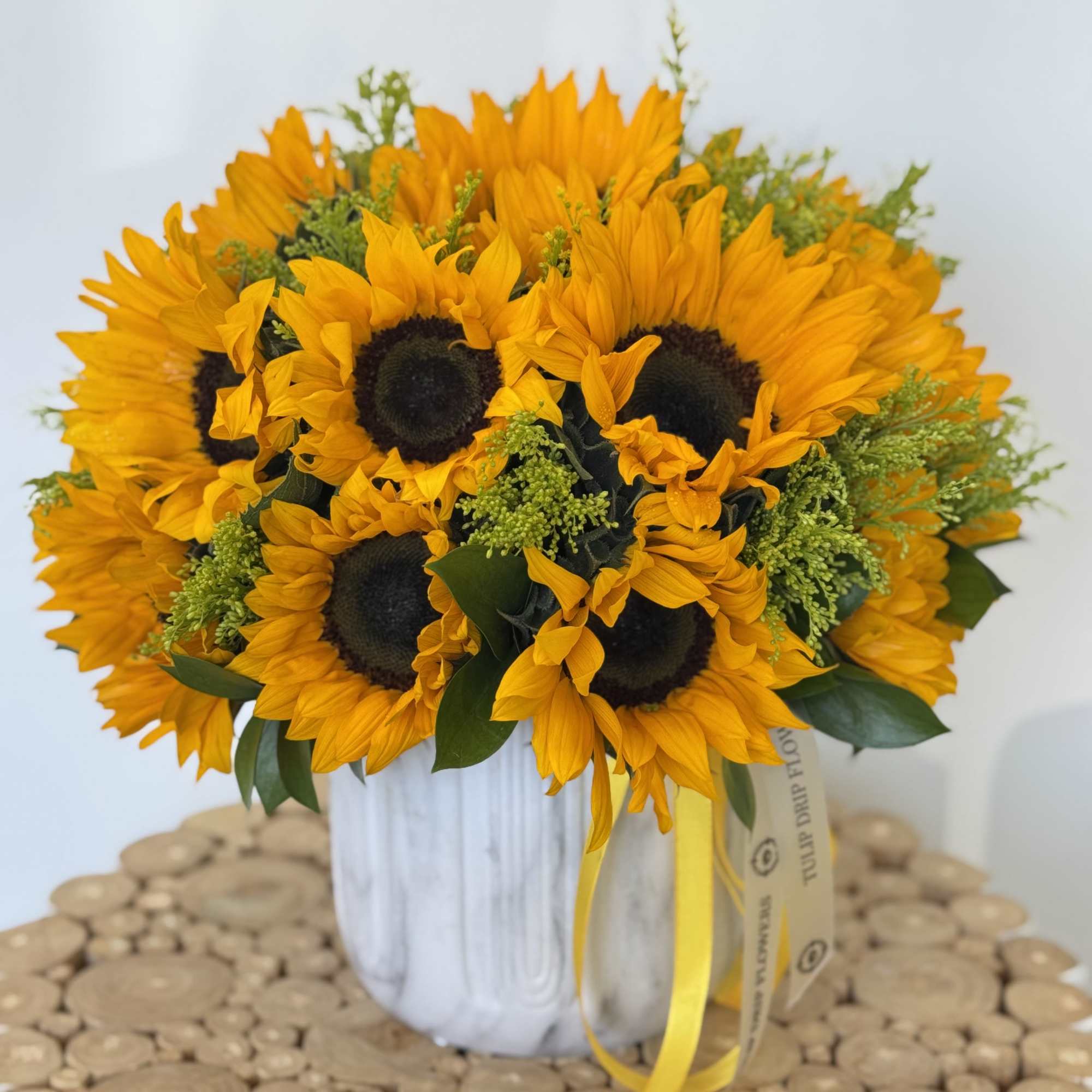 A stunning ceramic vase filled with vibrant sunflowers, complemented by Solidagos. 