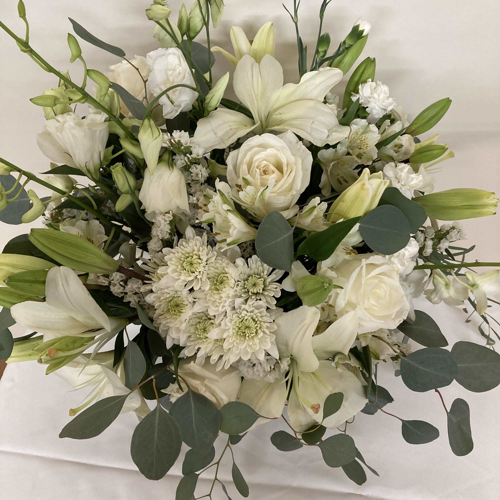 White lilies and roses set in the embrace of eucalyptus.