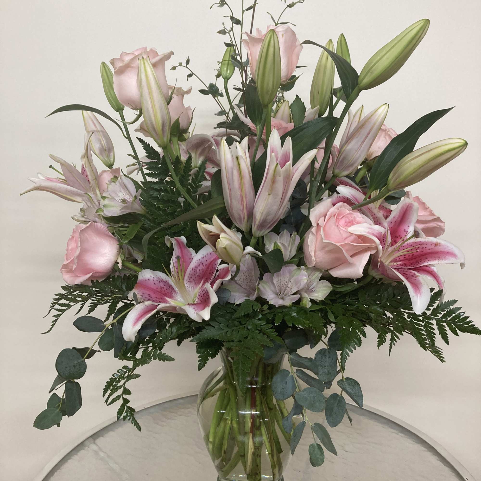 Stargazers and pink roses share space among the eucalyptus and leatherleaf.