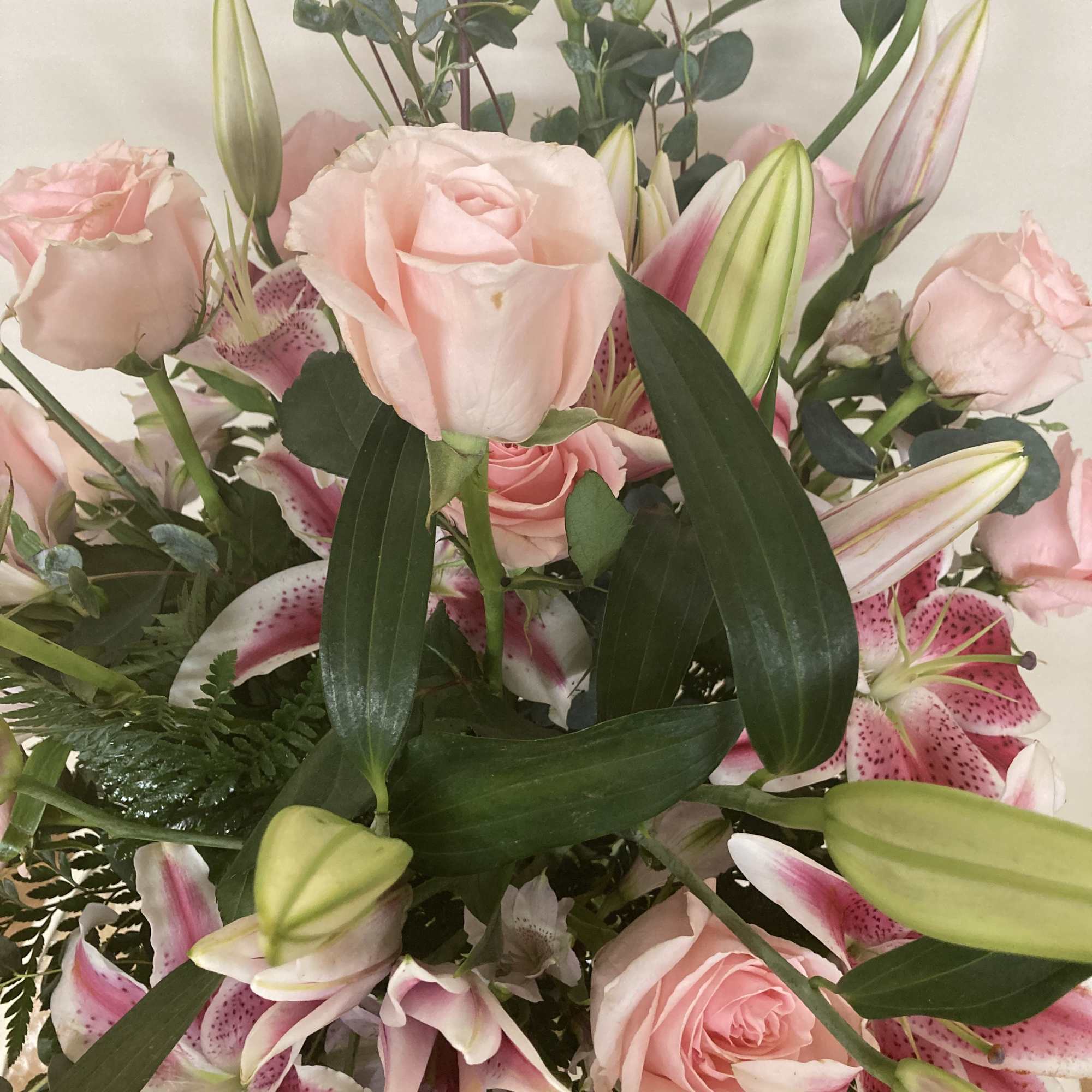 Stargazers and pink roses share space among the eucalyptus and leatherleaf.