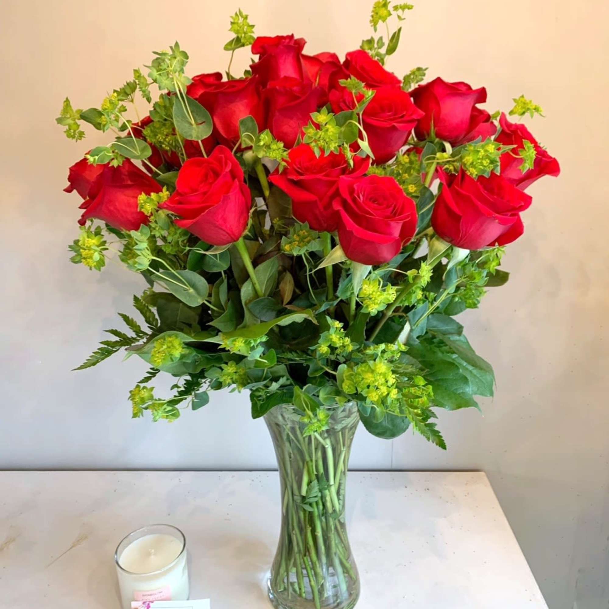 Premium long stem red roses with seasonal greenery in a tall clear
