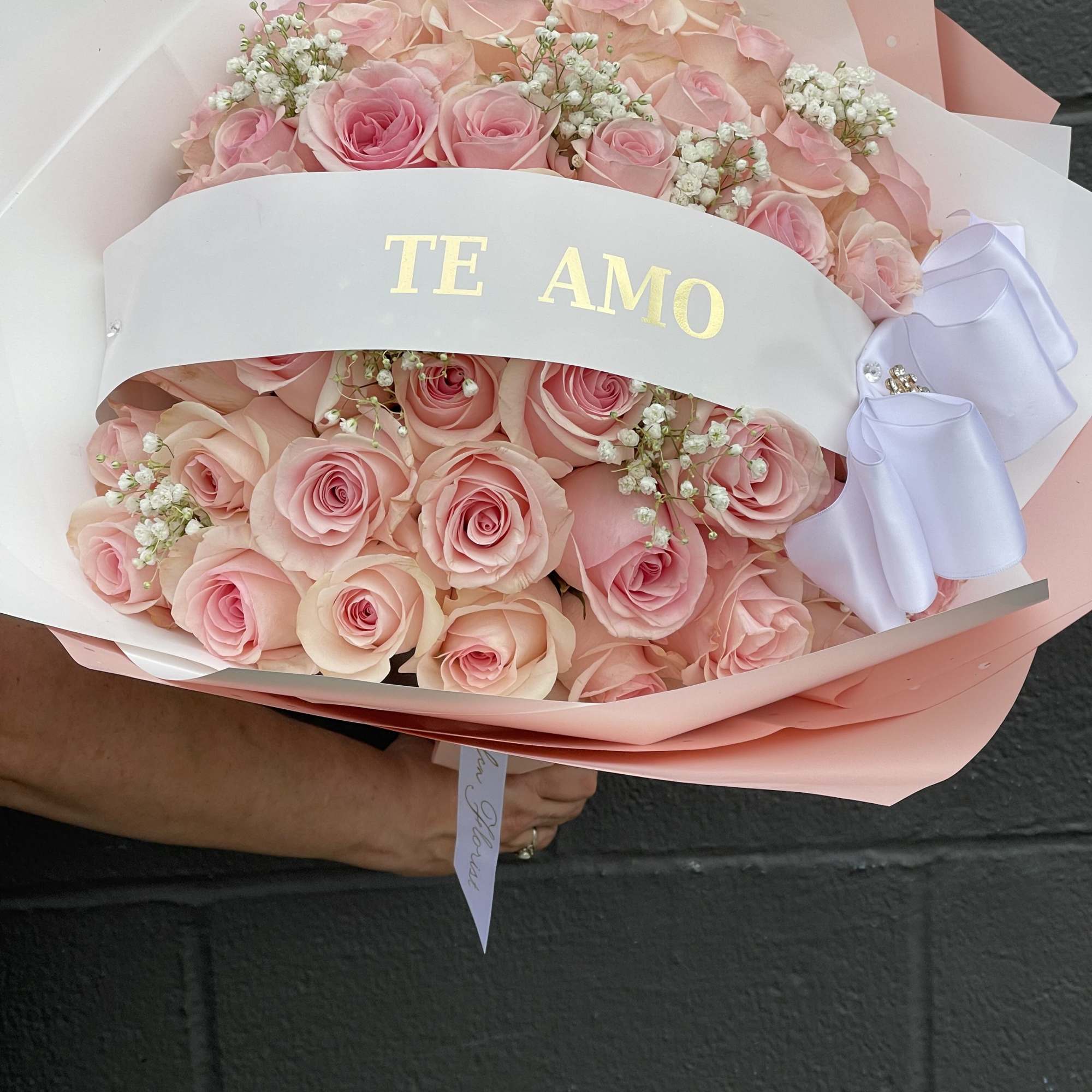 50 light pink long stem roses paired with an elegant ribbon and