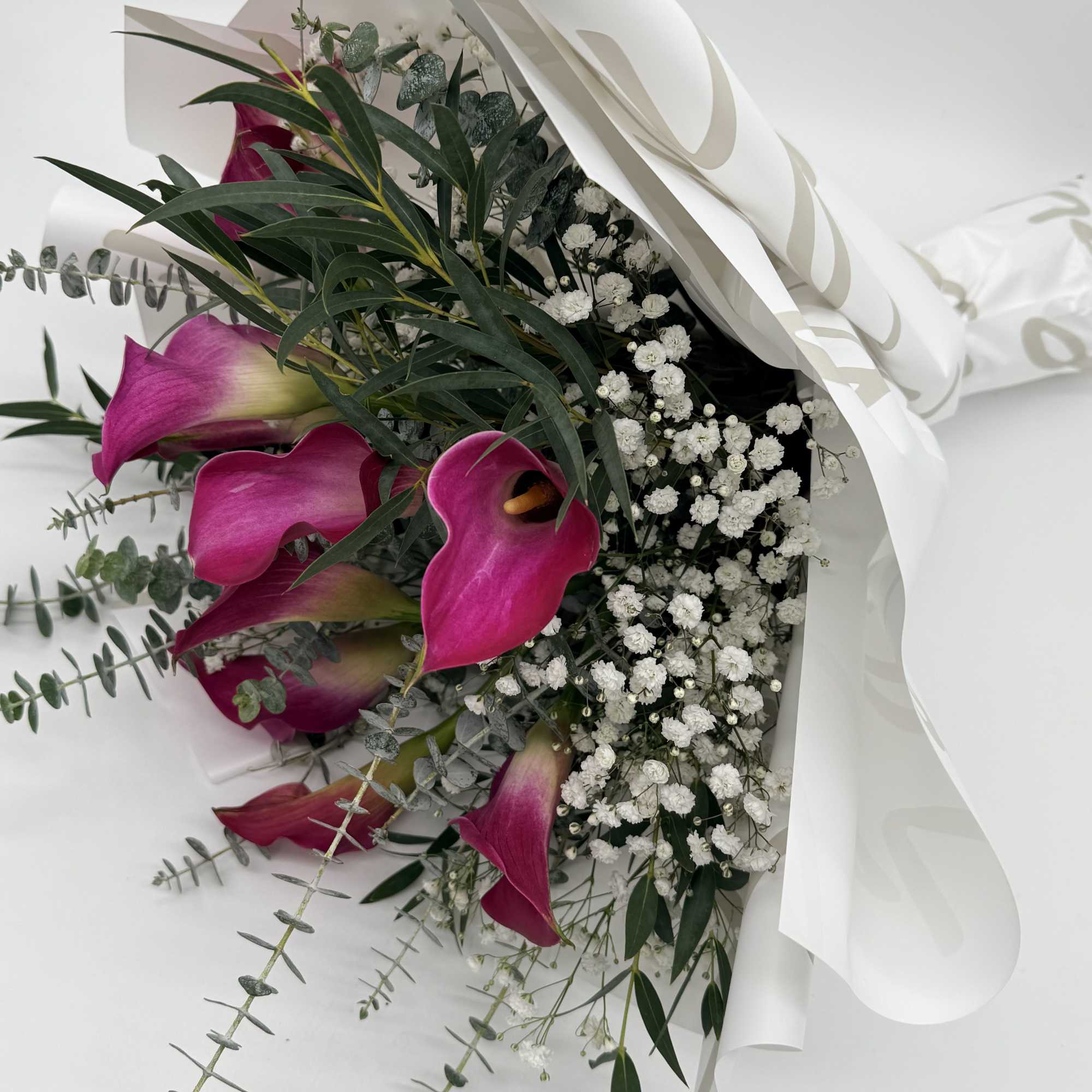 Graceful calla lilies take center stage in this elegant wrapped bouquet, accented