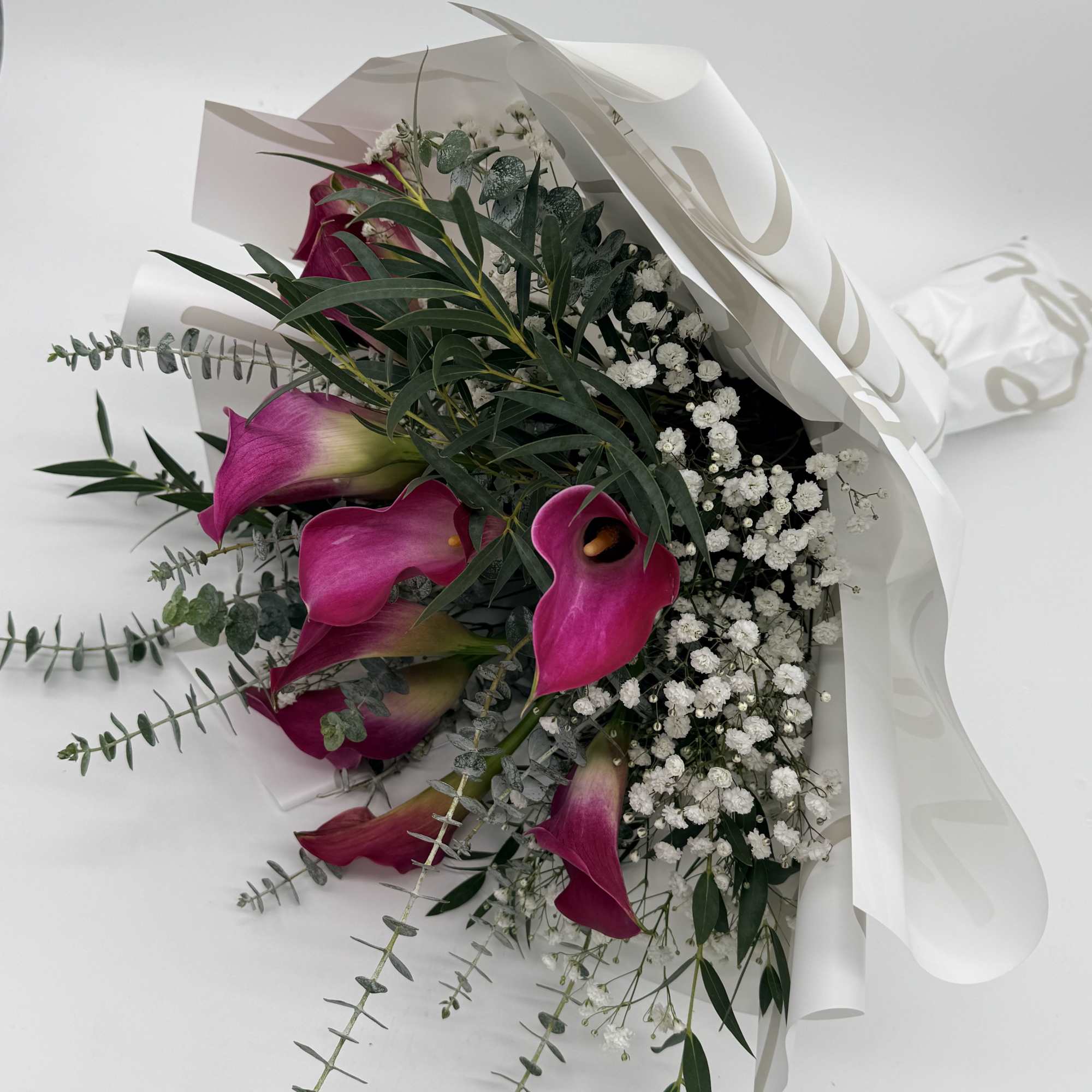 Graceful calla lilies take center stage in this elegant wrapped bouquet, accented