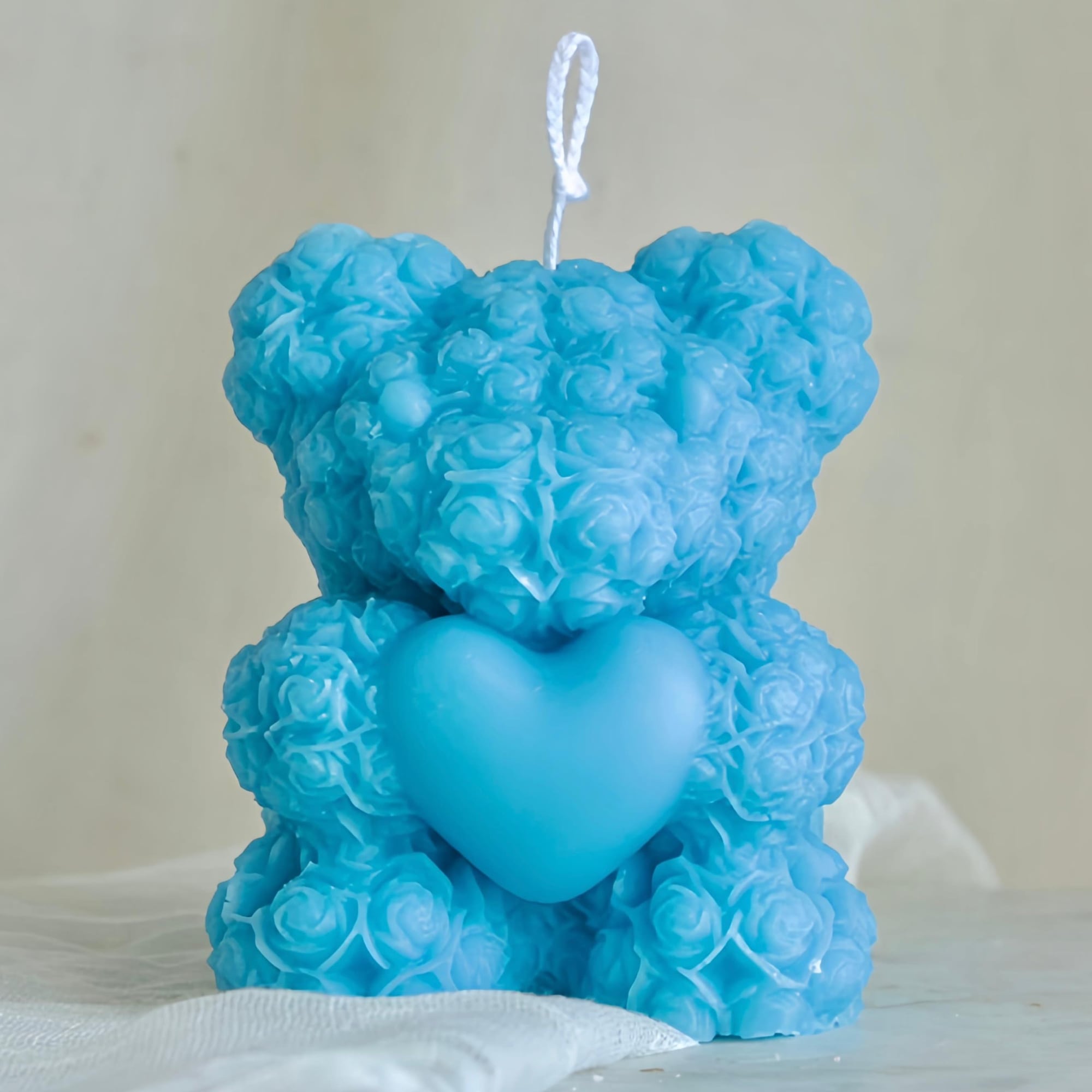A handmade teddy bear candle crafted from delicate rose-shaped wax details. Perfect