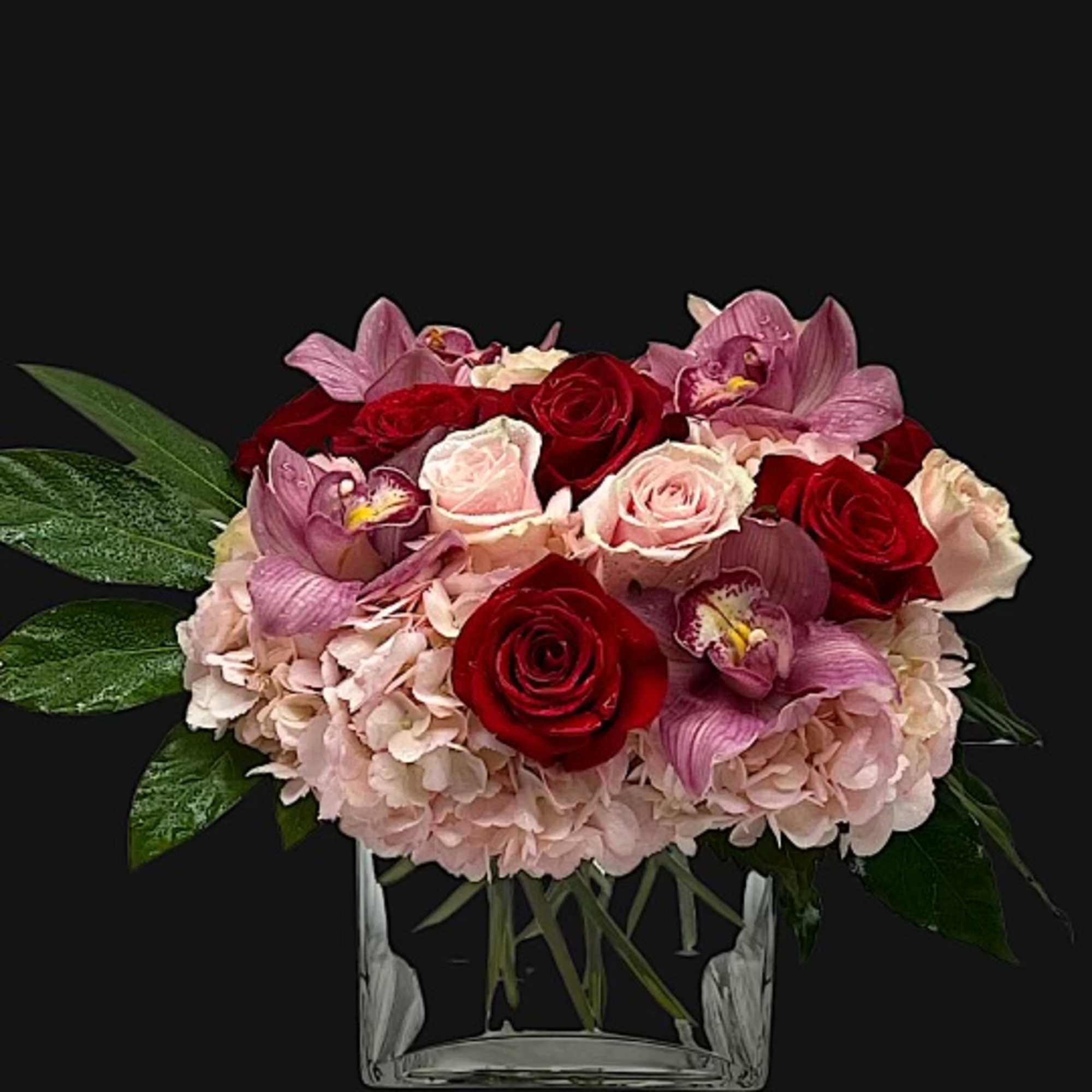 Beautifully designed pink hydrangeas, pink roses, red roses, and cymbidium orchids, with