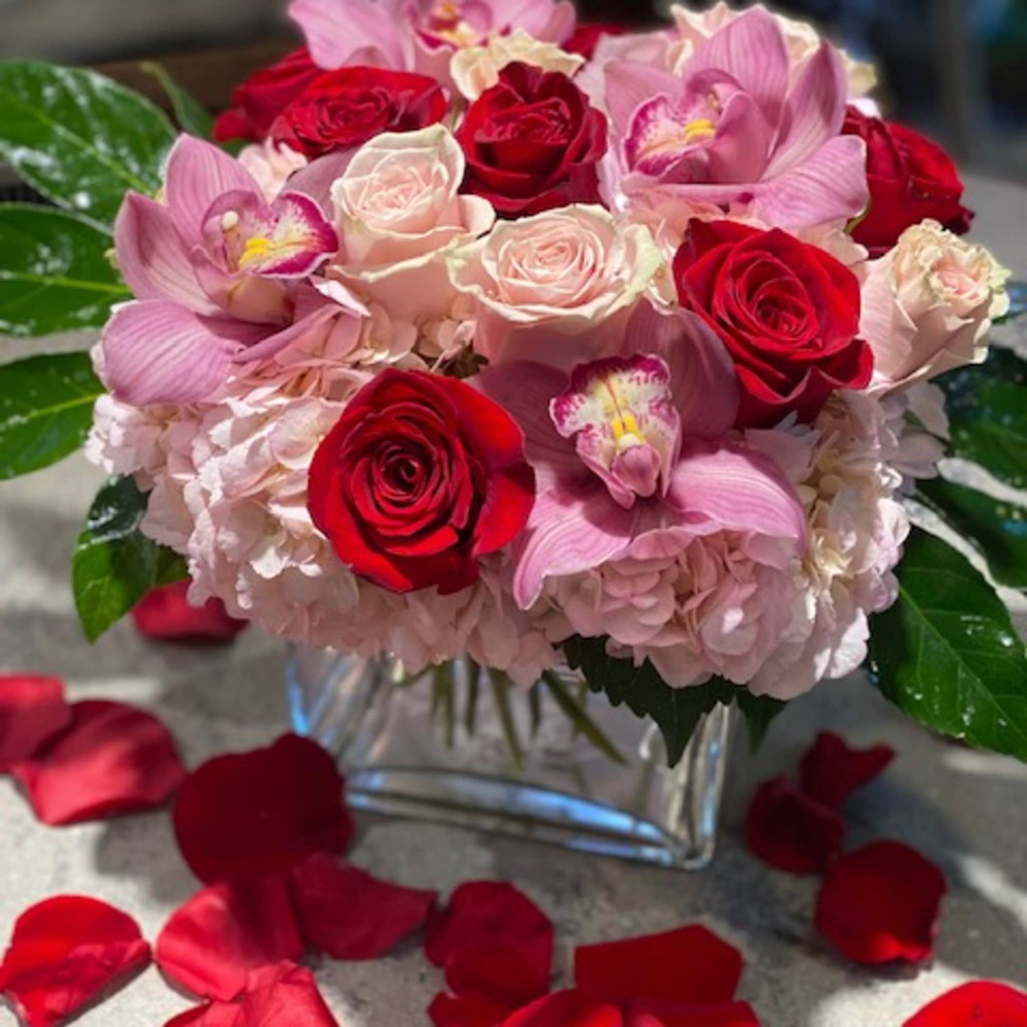 Beautifully designed pink hydrangeas, pink roses, red roses, and cymbidium orchids, with